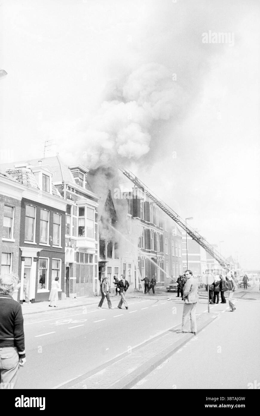 Incendie Haymarket Fire brigade Haarlem Hooimarkt pays-Bas, Whizgle News, Dutch Desk, pays-Bas, 1950 - 2000 on 26-06-1980. Voici les rubriques de l'image. Dans un cadre urbain animé, une scène dramatique se déroule sous forme d'épais panaches de fumée sombre provenant des étages supérieurs d'une rangée de bâtiments. La structure semble être une maison traditionnelle de deux ou trois étages, caractérisée par des briques et une architecture détaillée. Les flammes sont partiellement visibles à travers les fenêtres, ce qui laisse entendre l'intensité du feu. Les pompiers, vêtus d'un équipement de protection, sont engagés dans l'intervention d'urgence, en utilisant Banque D'Images