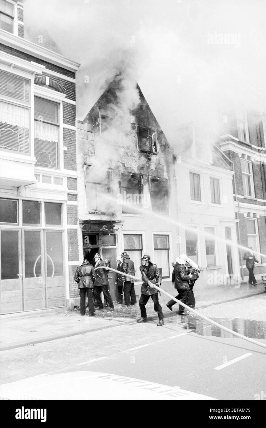 Incendie Haymarket Fire brigade Haarlem Hooimarkt pays-Bas, Whizgle News, Dutch Desk, pays-Bas, 1950 - 2000 on 26-06-1980. L'image inclut ces rubriques. La scène se déroule dans un environnement urbain caractérisé par une rangée de bâtiments, dont l'un en particulier montre des signes de dégâts importants. La structure endommagée semble avoir été engloutie dans les flammes, alors que la fumée s'écoule de ses niveaux supérieurs, créant un contraste frappant avec le ciel dégagé. La façade de ce bâtiment, autrefois probablement vibrante, révèle désormais du bois carbonisé et des fenêtres brisées. Les pompiers sont activement engagés dans la lutte Banque D'Images