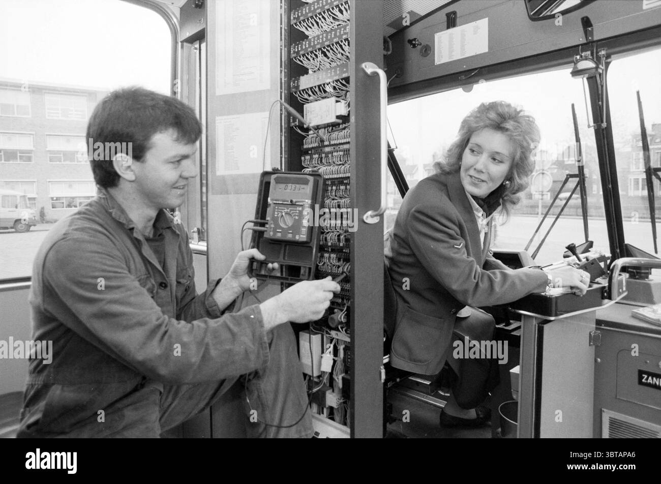 Divers plans à l'intérieur et à l'extérieur du bus NZH destinés à la publicité Noord Zuid Hollandse Vervoersmaatschappij N.V. NZ, Whizgle News, Dutch Desk, pays-Bas, 1950 - 2000 le 12-02-1987. Voici les rubriques de l'image. Dans un espace intérieur fonctionnel et bien éclairé, un homme et une femme sont engagés dans une conversation. L'homme, vêtu d'une combinaison de travail, est assis avec un focus sur un panneau de commande rempli de divers boutons et cadrans, indiquant un réglage technique. Il a une expression concentrée lorsqu'il ajuste quelque chose devant lui, suggérant qu'il est impliqué dans le dépannage ou la maintenance de e. Banque D'Images