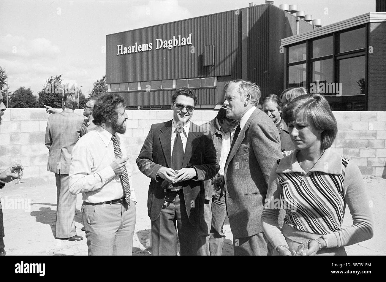 Boissons dans le bac à sable Haarlems Dagblad Haarlems Dagblad etc. et IJmuider courant et Koeri, Whizgle News, Dutch Desk, pays-Bas, 1950 - 2000 on 06-09-1976. Ces rubriques apparaissent dans l'image. Dans un cadre extérieur animé, un groupe de plusieurs personnes se réunit pour engager une conversation animée. La scène est vibrante mais décontractée, marquée par un mélange de tenues formelles et informelles. Un homme en costume, avec une barbe et des lunettes distinctives, apparaît animé pendant qu'il parle, faisant des gestes avec ses mains. Un autre homme, habillé de la même façon mais affichant un comportement plus détendu, se tient à côté de lui, hochant la tête et smi Banque D'Images