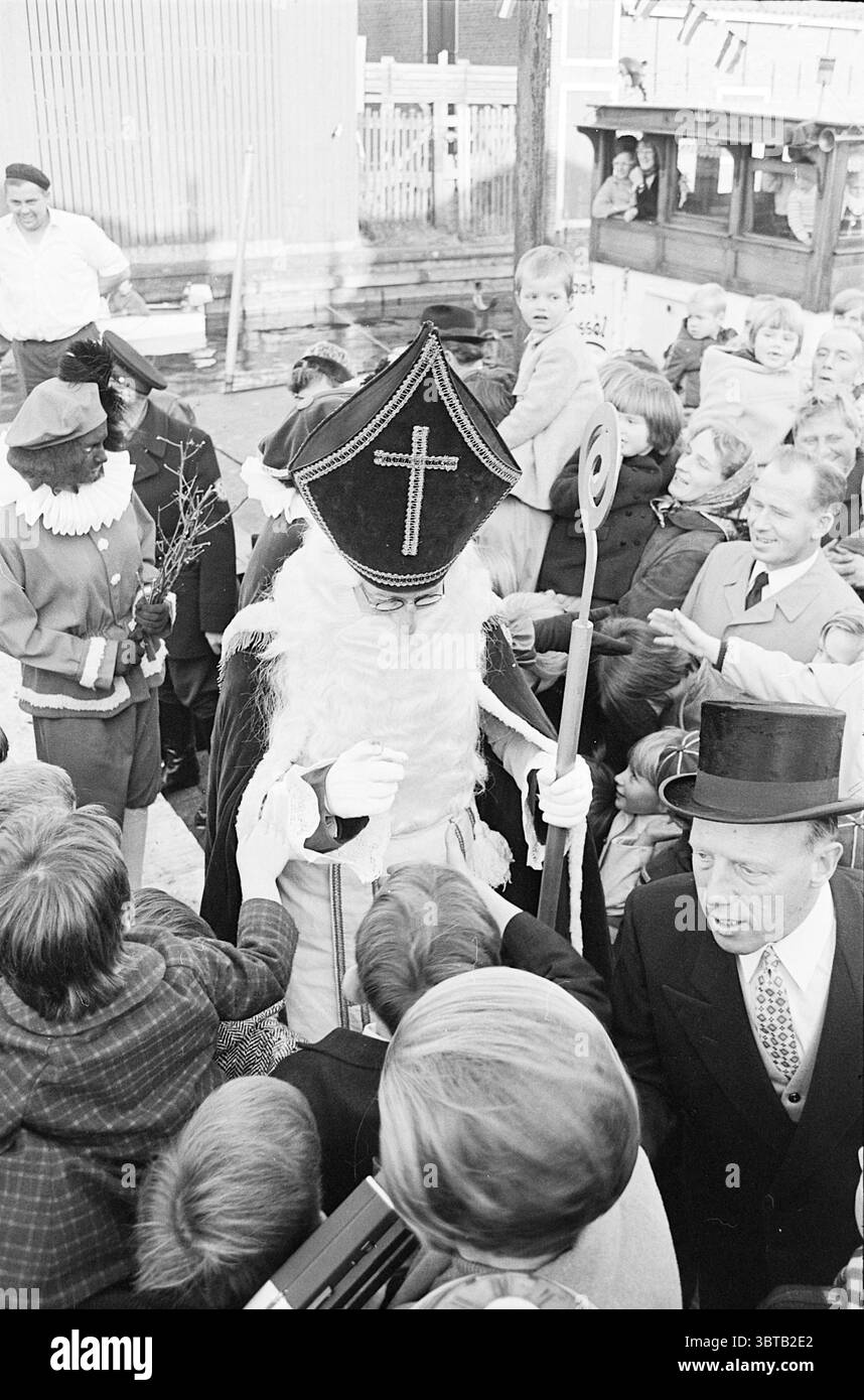 Nicholas in Hillegom rédigé Nicholas Sinterklaas, Whizgle News, Dutch Desk, The Netherlands, 1950 - 2000 on 18-11-1967. L'image inclut ces rubriques. Dans une scène animée en plein air, une figure habillée en saint avec une robe ornée et un chapeau élaboré se tient au centre, attirant l'attention. Le chapeau est noir avec une croix proéminente, et la figure tient également un bâton orné d'un sommet incurvé. Autour de ce personnage central, un groupe d'enfants excités se tend la main, leurs visages remplis de joie et d'anticipation, désireux de s'engager avec la figure. D'un côté, une personne habillée comme un traditionnel Banque D'Images