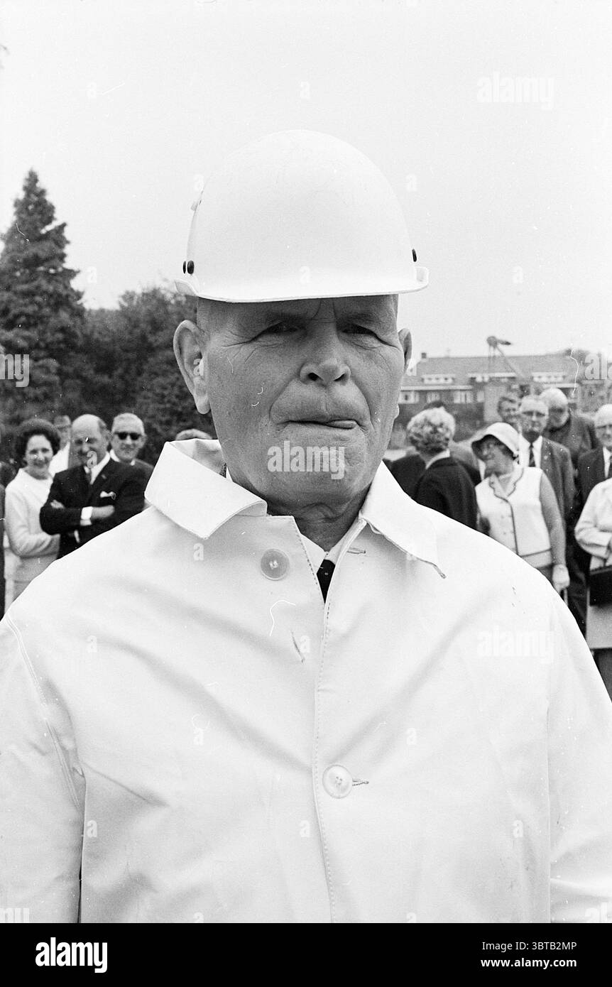 1ère ampoule perche premier pôle, Whizgle News, Dutch Desk, pays-Bas, 1950 - 2000 le 19-08-1969. Ces rubriques sont illustrées dans l'image. La scène capture un rassemblement d'individus, principalement habillés en tenue formelle ou chic-décontractée, suggérant un événement qui pourrait être significatif ou cérémoniel. Au premier plan se trouve un homme portant un casque blanc, ce qui implique qu'il peut être impliqué dans la construction ou un contexte d'ingénierie. Son expression est sérieuse, ajoutant un sentiment d'autorité ou de concentration à la scène. Il est vêtu d'un manteau de couleur claire, peut-être blanc, qui contraste avec le cl plus sombre Banque D'Images