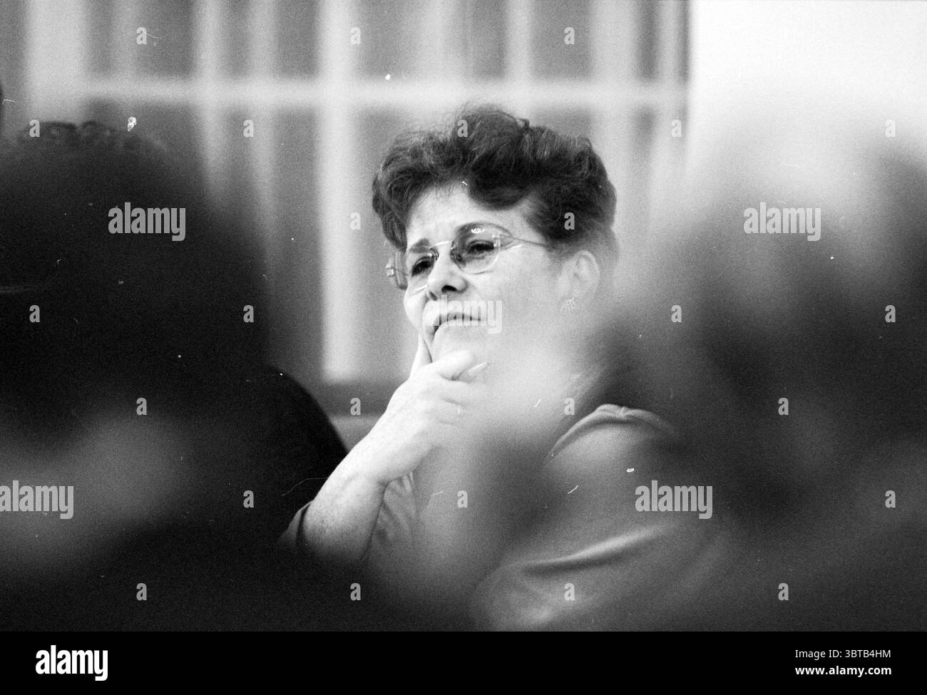 Conseillers budgétaires H'lem Haarlem Grote Markt 2 pays-Bas, Whizgle News, Dutch Desk, pays-Bas, 1950 - 2000 on 03-11-1996. Ce sont les éléments de l'image. La scène capture une vue rapprochée d'une femme qui apparaît profondément dans la pensée. Ses cheveux sont coiffés en vagues douces, encadrant son visage et soulignant doucement son expression contemplative. Elle porte des lunettes, les lentilles brillent subtilement dans la lumière, et son menton repose soigneusement sur sa main. Une palette neutre domine l'environnement, avec des gris doux et des tons doux créant une atmosphère d'introspection. L'arrière-plan est légèrement Banque D'Images