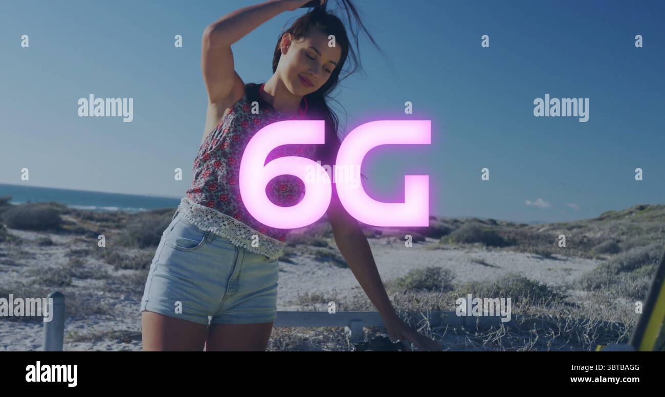 Femme debout dans le haut floral retenant les cheveux en arrière à côté de voiture à coffre ouvert à la côte sablonneuse, brillant 6G. Banque D'Images