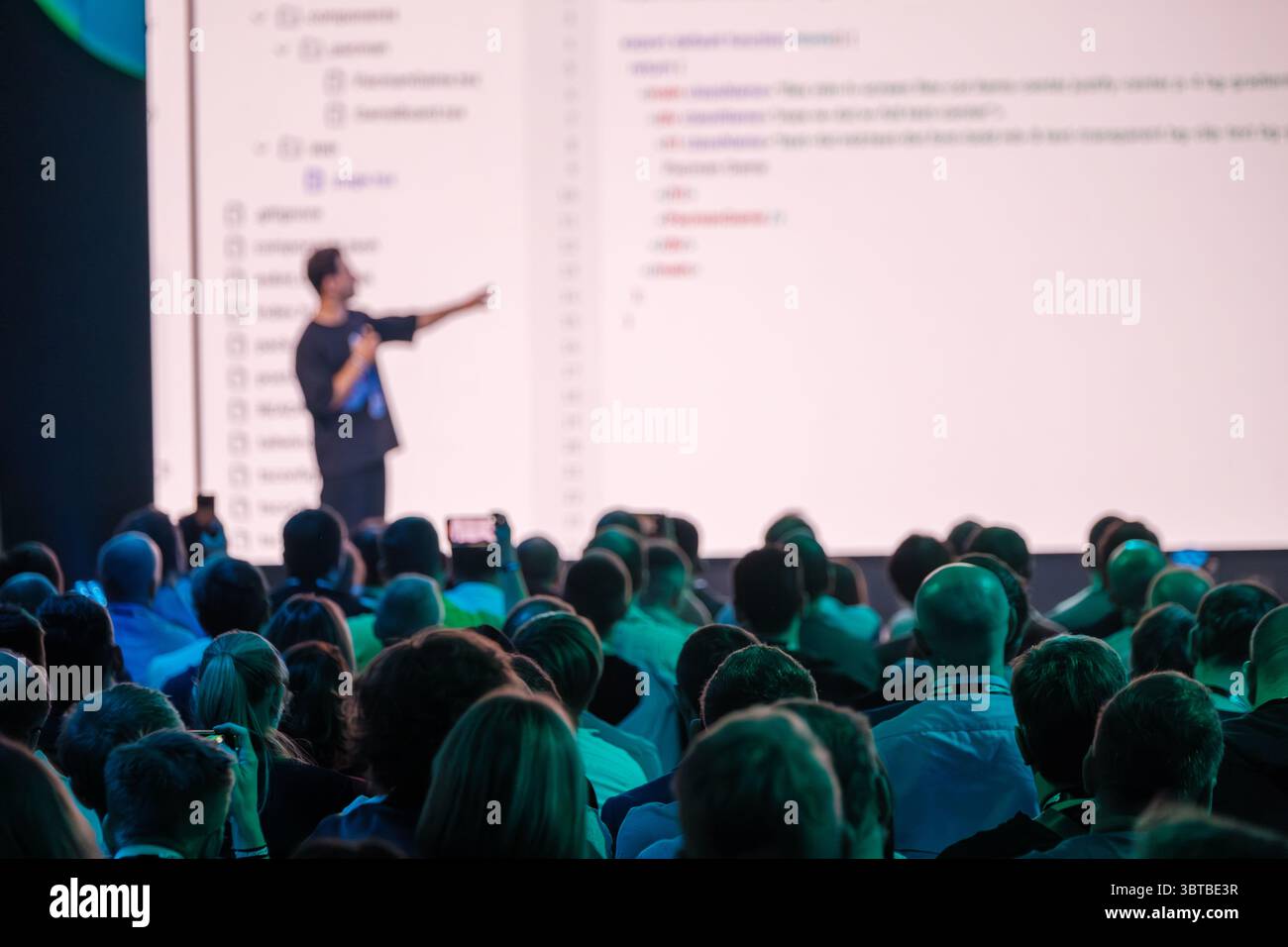 Conférence engageante avec conférencier présentant les concepts de programmation au public. Grand écran affichant le code. Banque D'Images