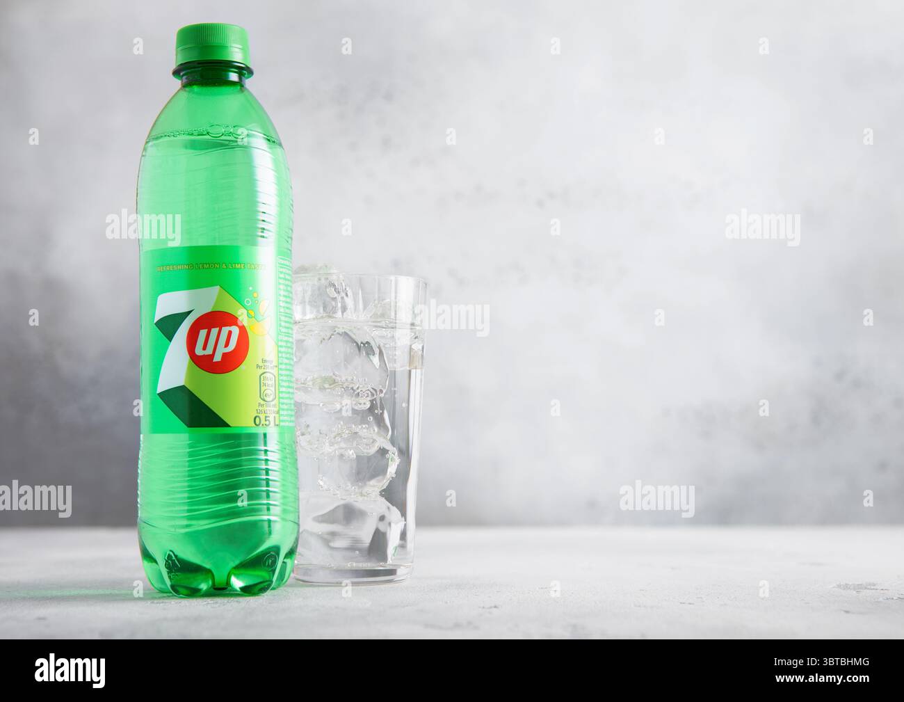 LONDRES, Royaume-Uni - 27 JUIN 2025 : bouteille en plastique de boisson gazeuse au citron vert et au citron 7UP avec verre et glaçons sur table lumineuse. Banque D'Images