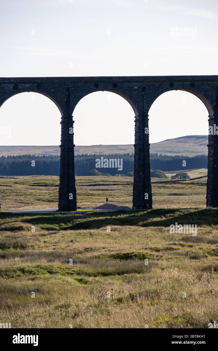 Une personne se tenait sous les arches du viaduc Ribblehead sur la ligne Settle-Carlisle dans le Yorkshire Dales National Park en Angleterre par une journée ensoleillée. Banque D'Images