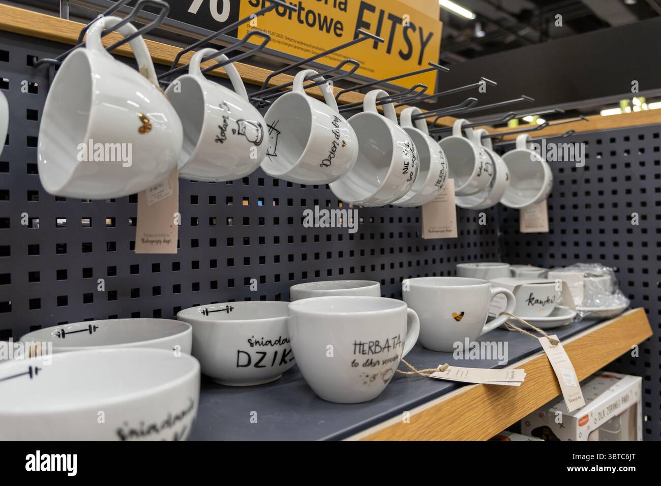 Poznan, Pologne - 30 juin 2025 : une vue rapprochée de tasses et bols en céramique blanche soigneusement disposés avec des dessins conceptuels, présentés dans un magasin dynamique Banque D'Images