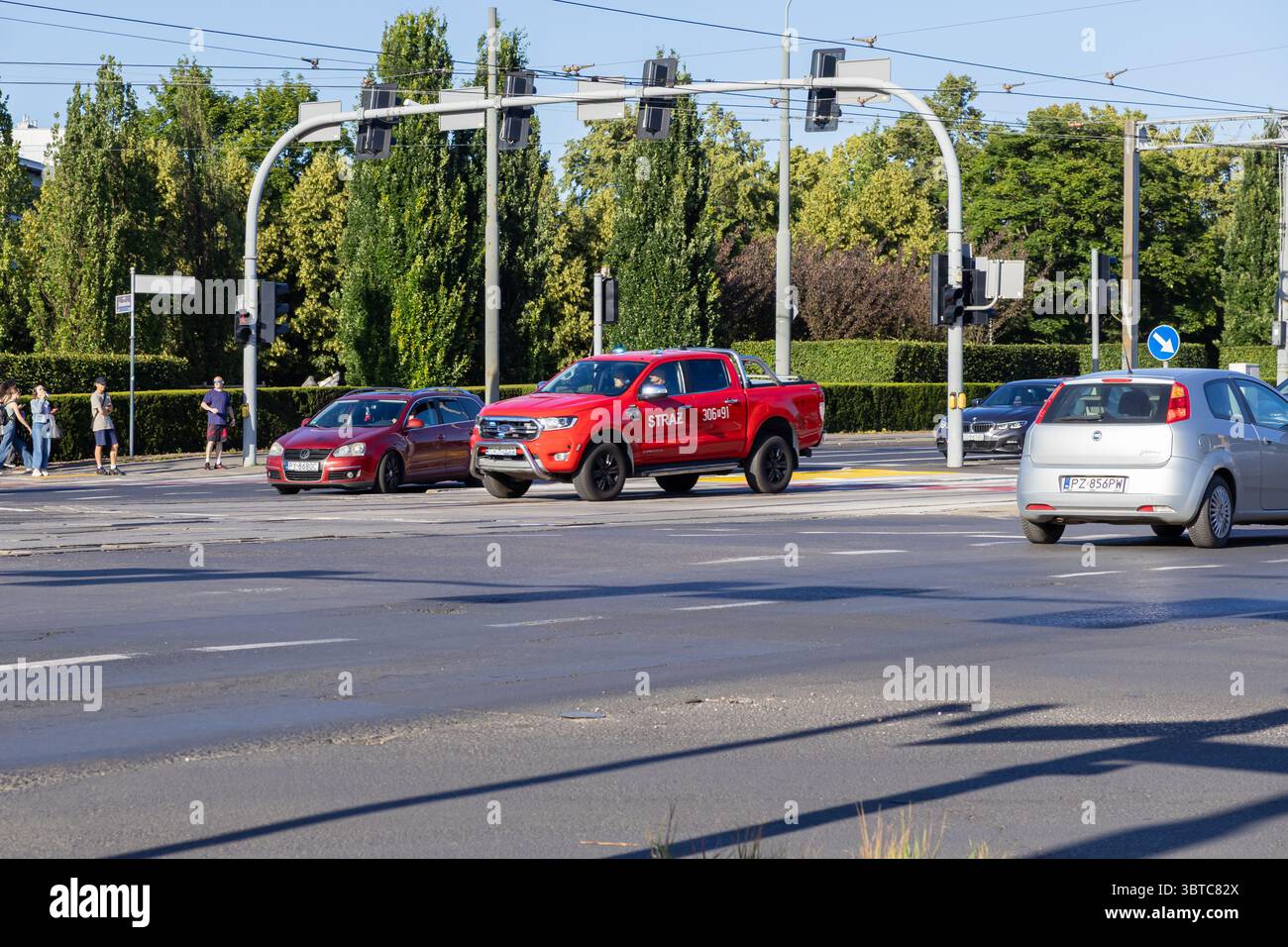 Poznan, Pologne - 30 juin 2025 : une camionnette rouge du service d'incendie STRAZ, utilisée par les services d'urgence, manœuvre dans une rue urbaine animée avec v Banque D'Images