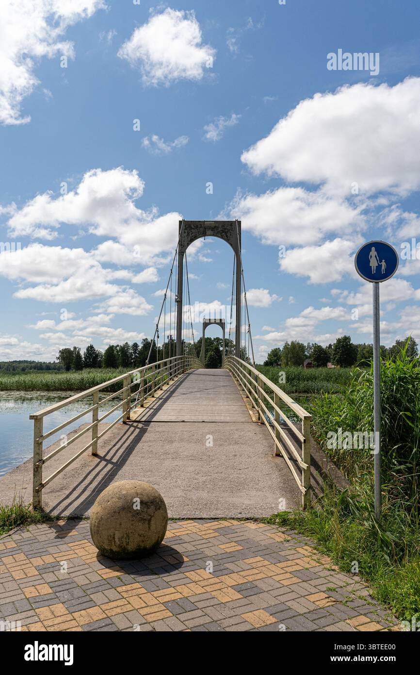 Pont piétonnier au-dessus de l'eau à Võru, Estonie, avec garde-corps métalliques, trottoir en pierre et signalisation – infrastructure urbaine fonctionnelle et pittoresque. Banque D'Images