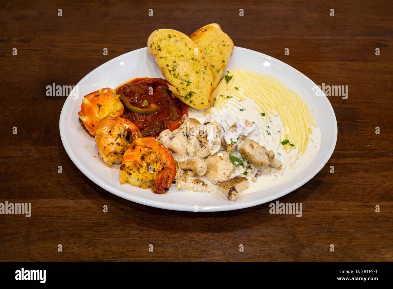 Spécial du chef avec crevettes royales, poulet à la sauce blanche, purée de pommes de terre et pain à l’ail Banque D'Images
