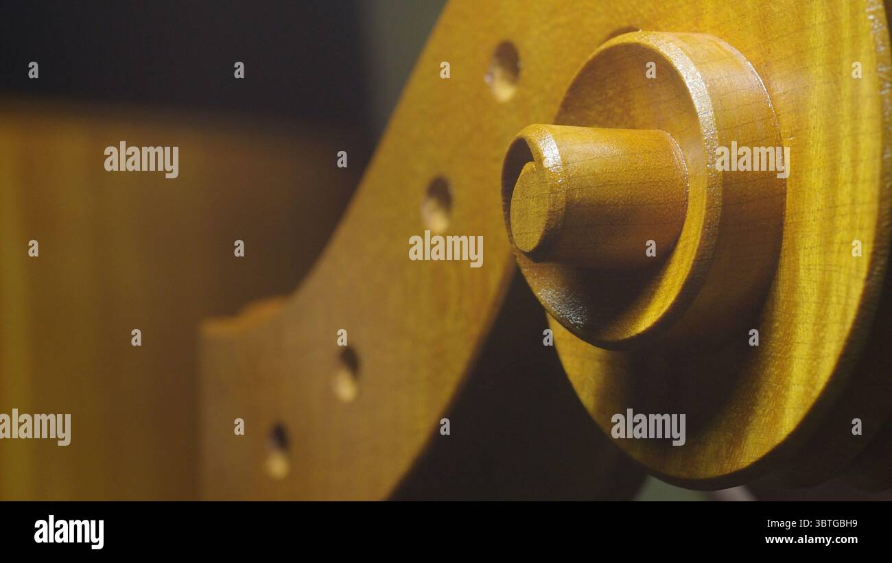 Vue détaillée d'un rouleau de violoncelle dans un atelier, mettant en valeur le savoir-faire complexe impliqué dans la fabrication de violons. L'image met en valeur le bois lisse Banque D'Images
