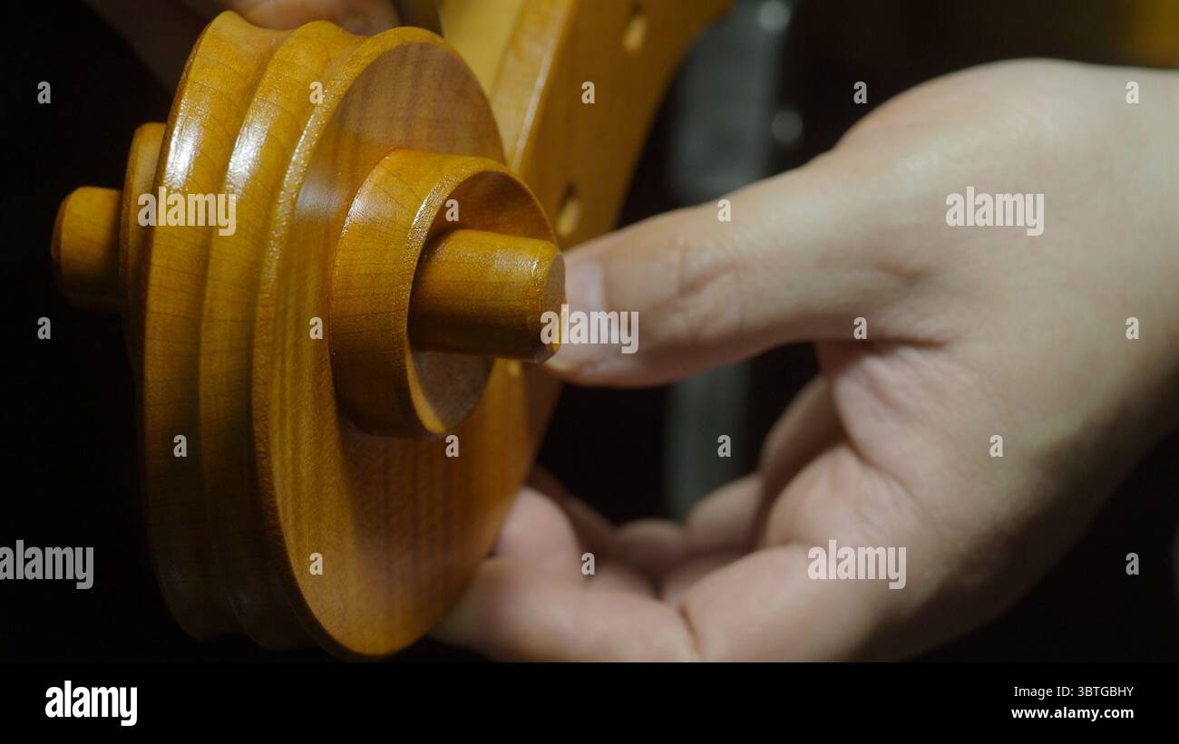 Luthier examinant soigneusement et ajustant une cheville d'accord en bois finement conçue, assurant un ajustement précis et un fonctionnement fluide pour un mécanisme d'accord de violoncelle Banque D'Images