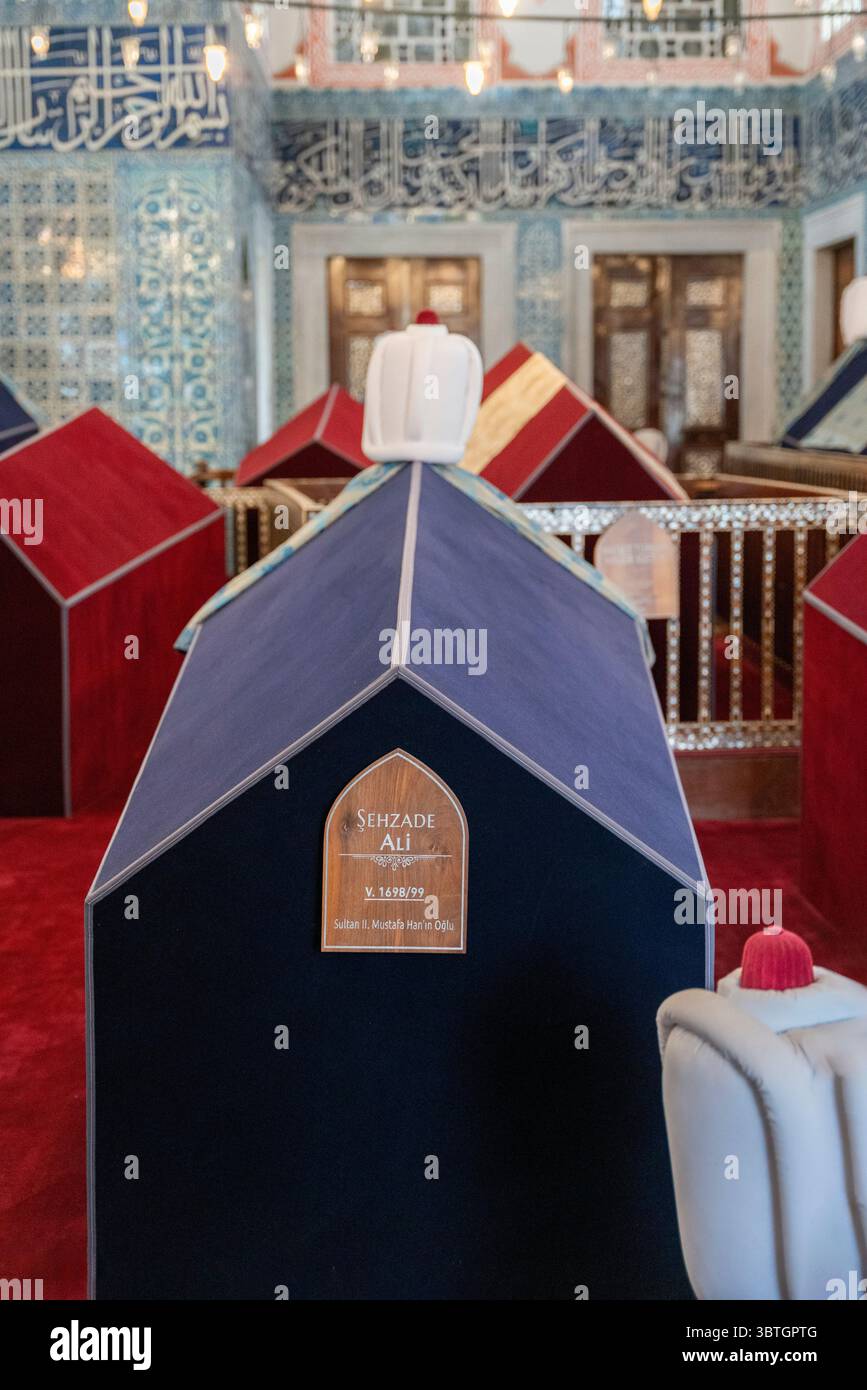 L'intérieur du tombeau du sultan Turhan à Istanbul, en Turquie, avec des sarcophages recouverts de tissu entourés de murs ornés de tuiles Iznik détaillées Banque D'Images