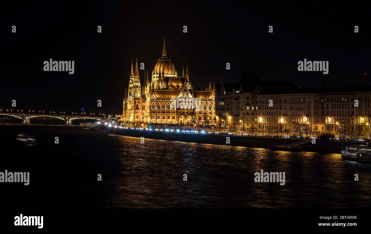 Parlement hongrois illuminé reflétant dans le Danube la nuit, paysage urbain emblématique et architecture à Budapest, Hongrie, mars 2025 Banque D'Images