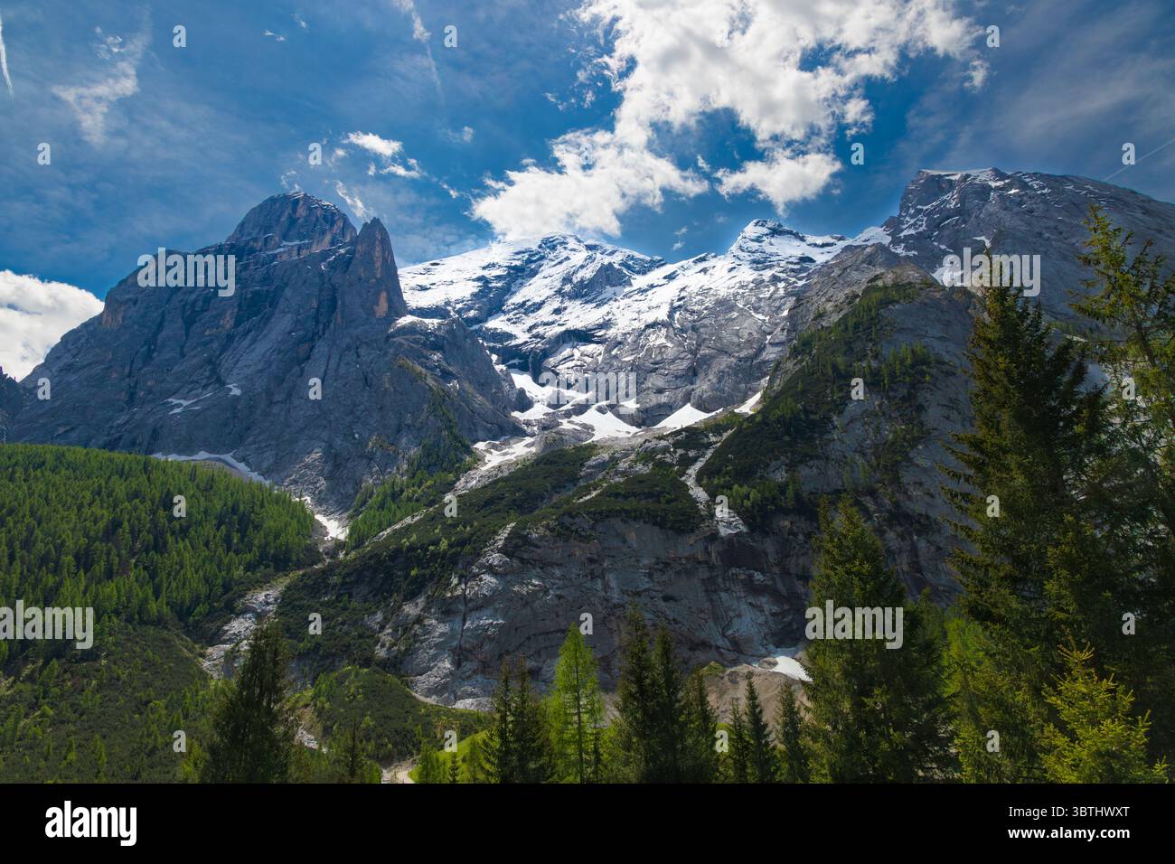 Les imposants sommets enneigés de Marmolada, Reine des Dolomites, se dressent majestueusement contre un ciel bleu éclatant avec des nuages éparpillés. Banque D'Images