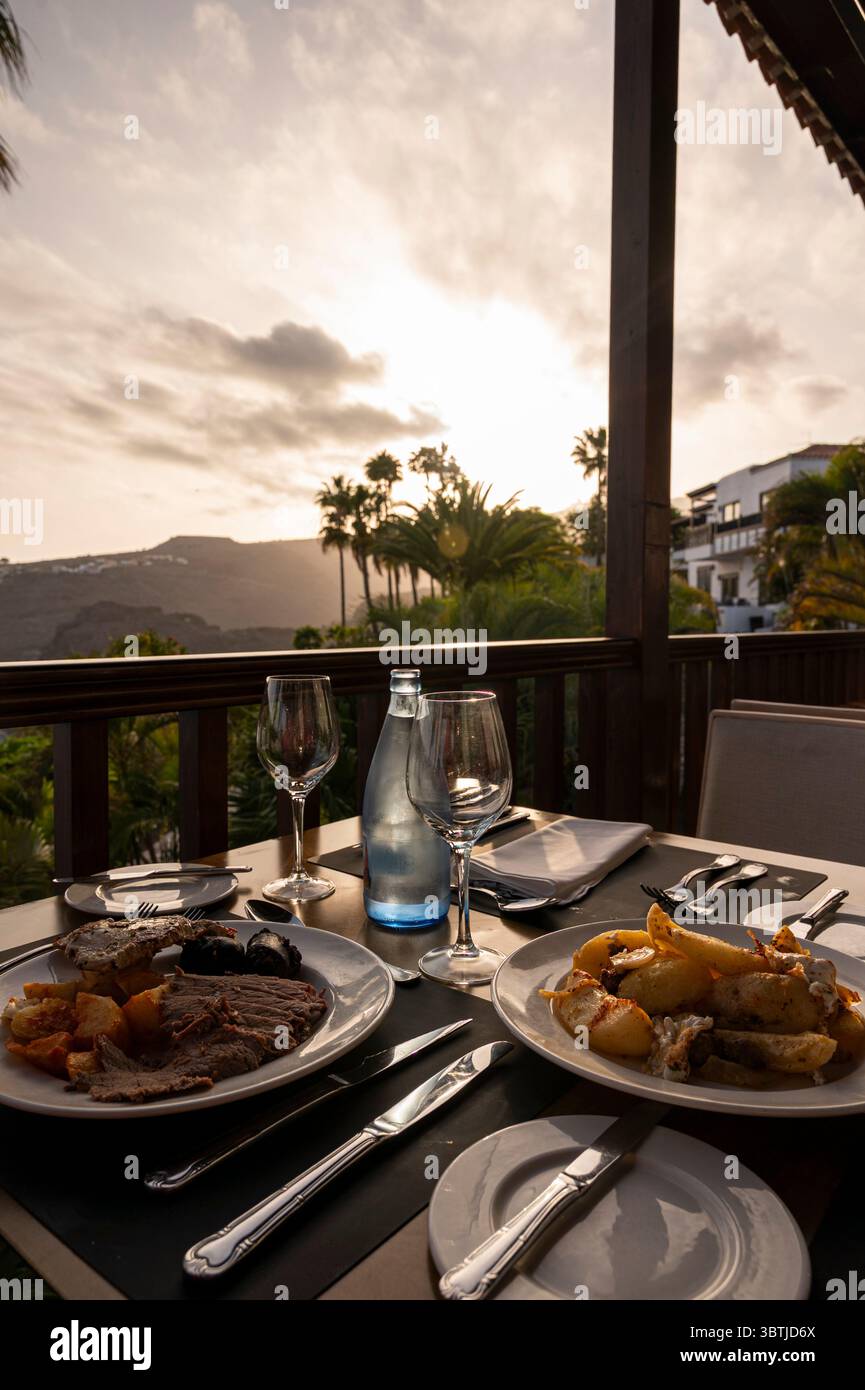 Une table avec deux assiettes de nourriture et deux verres à vin. La table est fixée pour deux personnes et l'ambiance est détendue et intime Banque D'Images