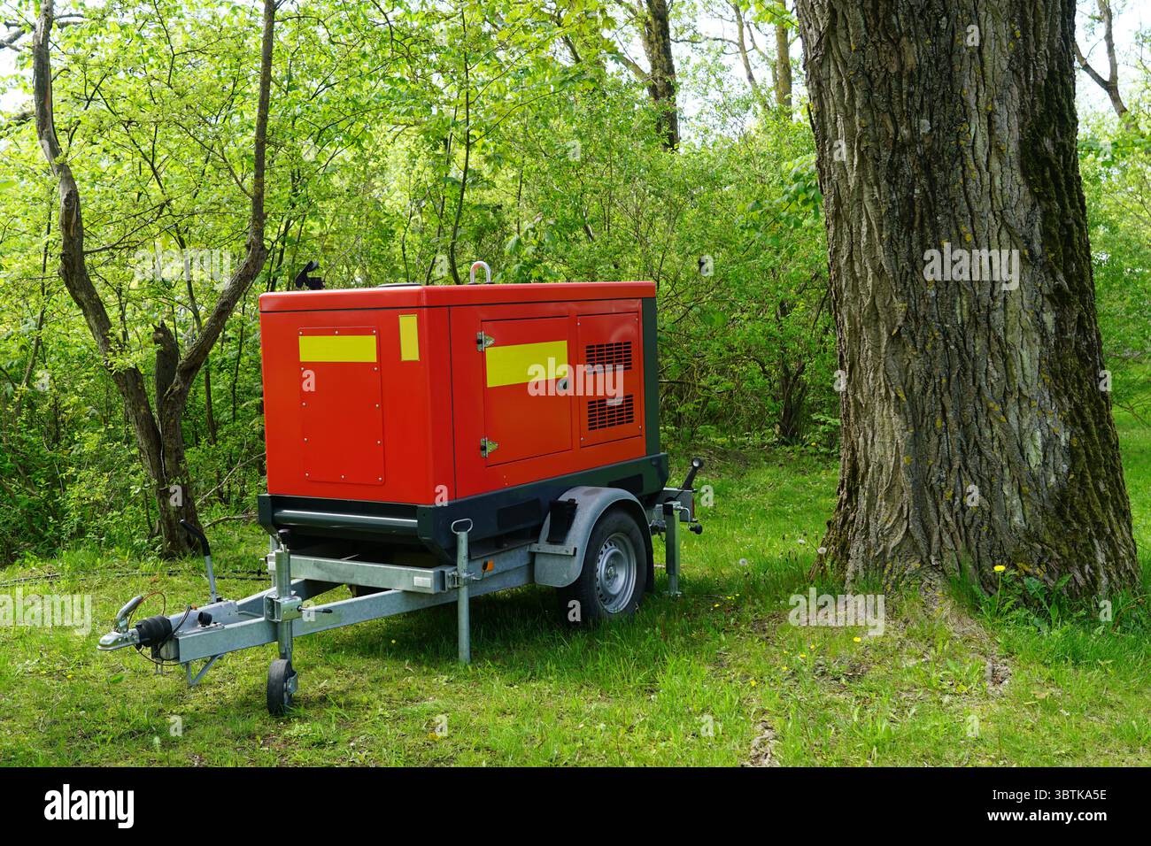 Une génératrice portable rouge se trouve sur une remorque dans le parc, fournissant de l'énergie pour les activités de plein air Banque D'Images