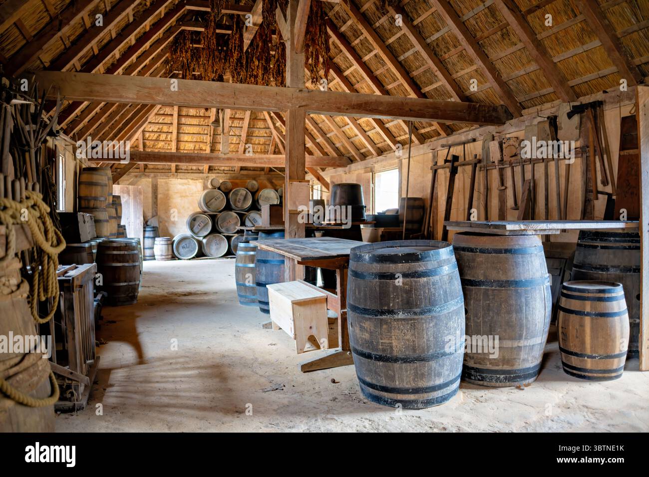 Jamestown Settlement Storage Building Barrels Jamestown Virginia // JAMESTOWN, Virginia — Un bâtiment de stockage expose des barils, de l'équipement et des fournitures dans le fort James recréé à Jamestown Settlement. Le fort représente l'avant-poste militaire de la Virginia Company de Londres tel qu'il apparaissait en 1610-14, représentant le début de la période coloniale lorsque les colons anglais ont établi leur pied dans le Nouveau monde. Le musée de l'histoire vivante présente des structures de toit de chaume, y compris une église anglicane, une cour de garde, un entrepôt et la maison du gouverneur qui témoignent de la vie quotidienne dans les fortifications Banque D'Images
