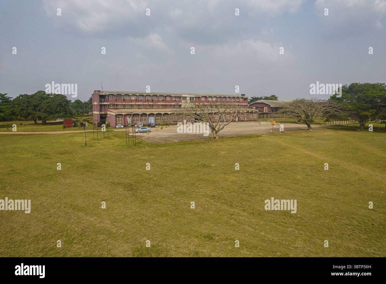 Vue aérienne d'un grand complexe de bâtiments avec un toit rouge et plusieurs étages entouré d'un large champ d'herbe sèche, Enugu, Nigeria. Banque D'Images