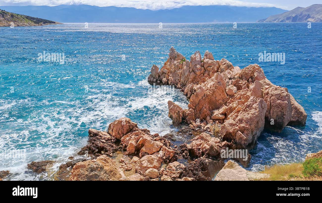 Côte rocheuse avec une mer turquoise et des vagues écrasantes sous un temps ensoleillé. Banque D'Images