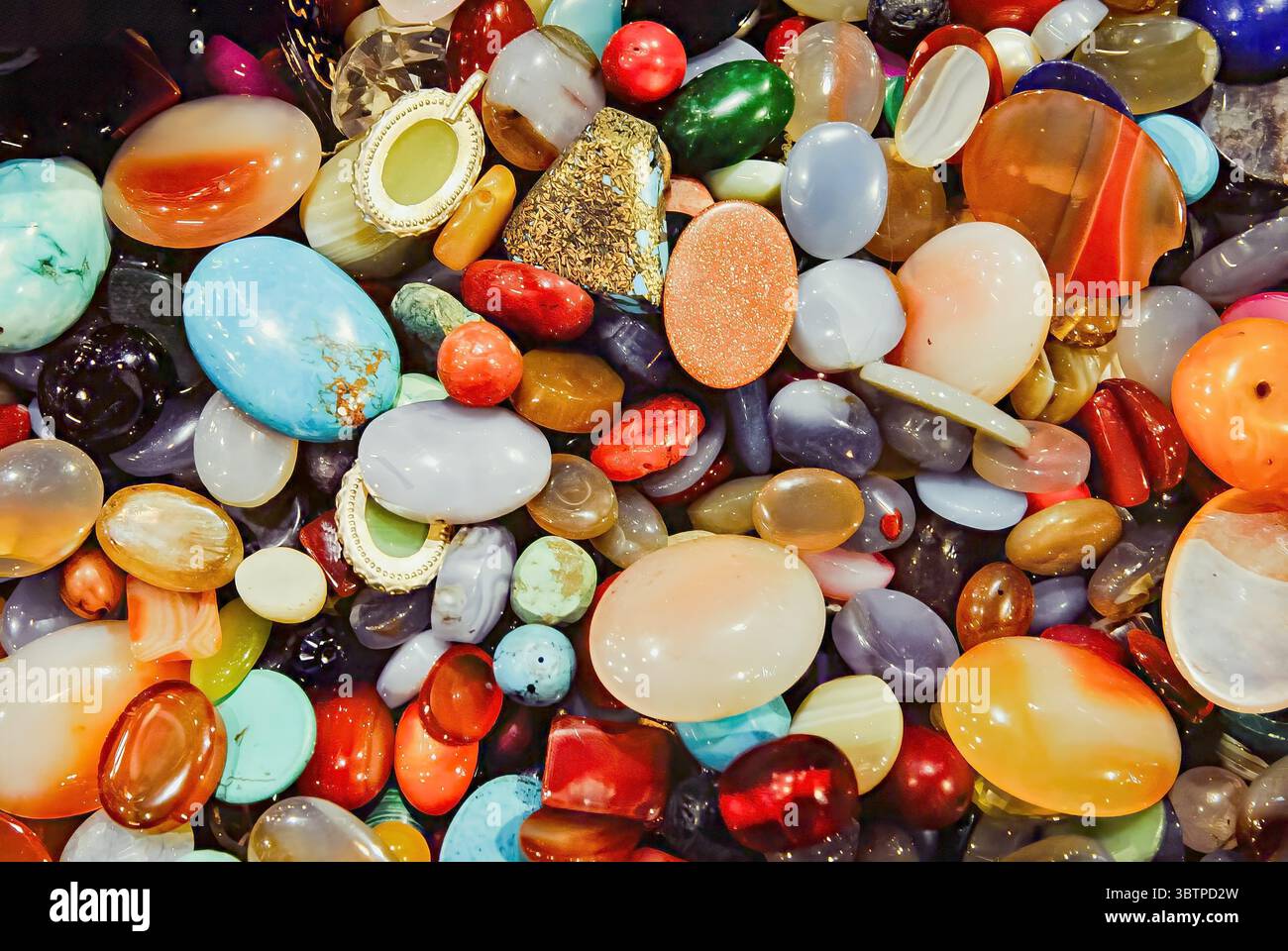 Pierres précieuses polies colorées assorties dans une vue rapprochée. Variété de formes, de textures et de couleurs vibrantes. Banque D'Images