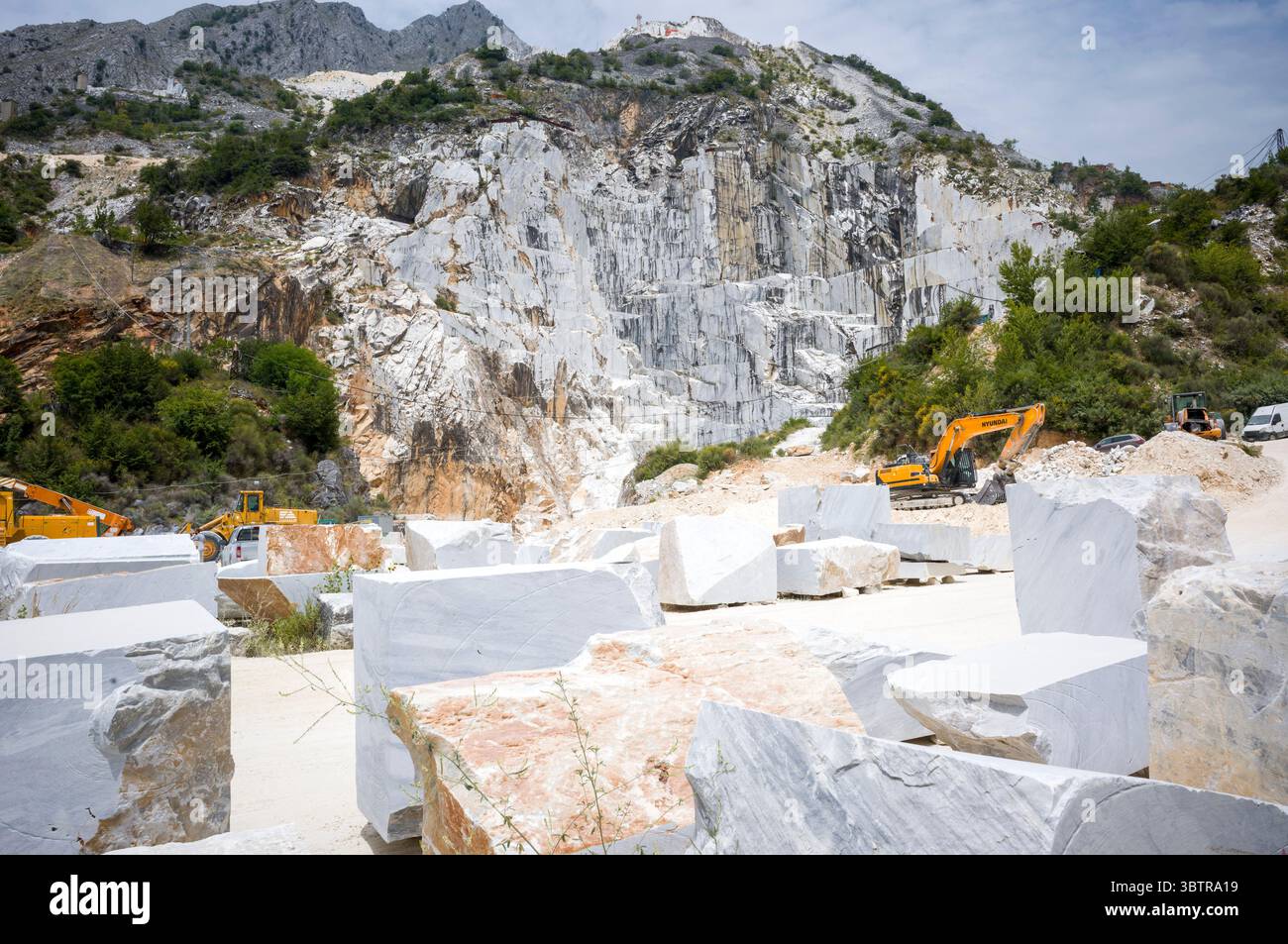 Excavatrice à la carrière de marbre dans les Alpes Apuanes produisant le célèbre marbre de Carrare, connu pour ses veines blanches et grises dans la province de Massa et Carra Banque D'Images