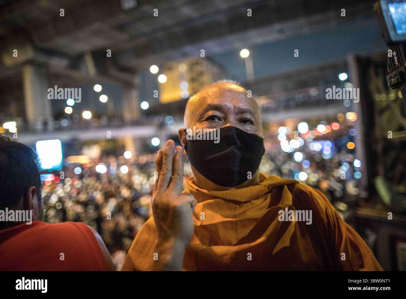 21 octobre 2020, Bangkok, Thaïlande : un moine bouddhiste thaïlandais vu en train de saluer à trois doigts avec la foule de manifestants pro-démocratie en arrière-plan lors d'une manifestation antigouvernementale dans la capitale thaïlandaise. Des milliers de manifestants pro-démocratie sont descendus dans les rues au Monument de la victoire pour exiger la démission du premier ministre thaïlandais et la réforme de la monarchie pour le septième jour après un état sévère de emergencyâ€˜de â€™ déclaré par le premier ministre Prayut Chan-o-cha. Les manifestants ont défilé du Monument de la victoire au Government House et ont remis une lettre au premier ministre Prayut Chan-o Banque D'Images