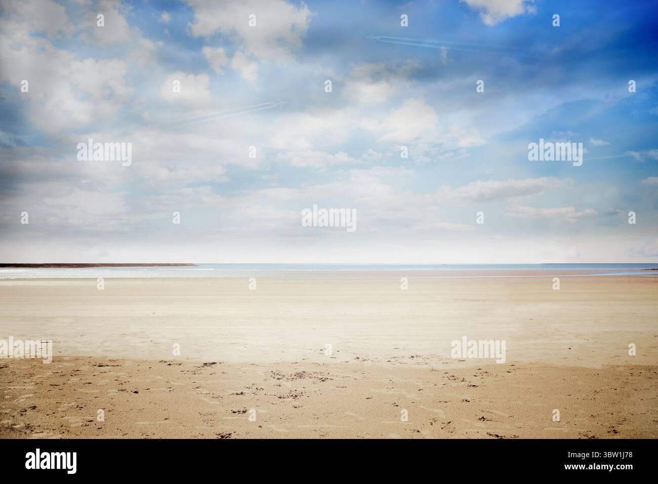 Plage de sable plate s'étendant à l'horizon, présentant du sable lisse, une mer calme et des nuages à la dérive Banque D'Images