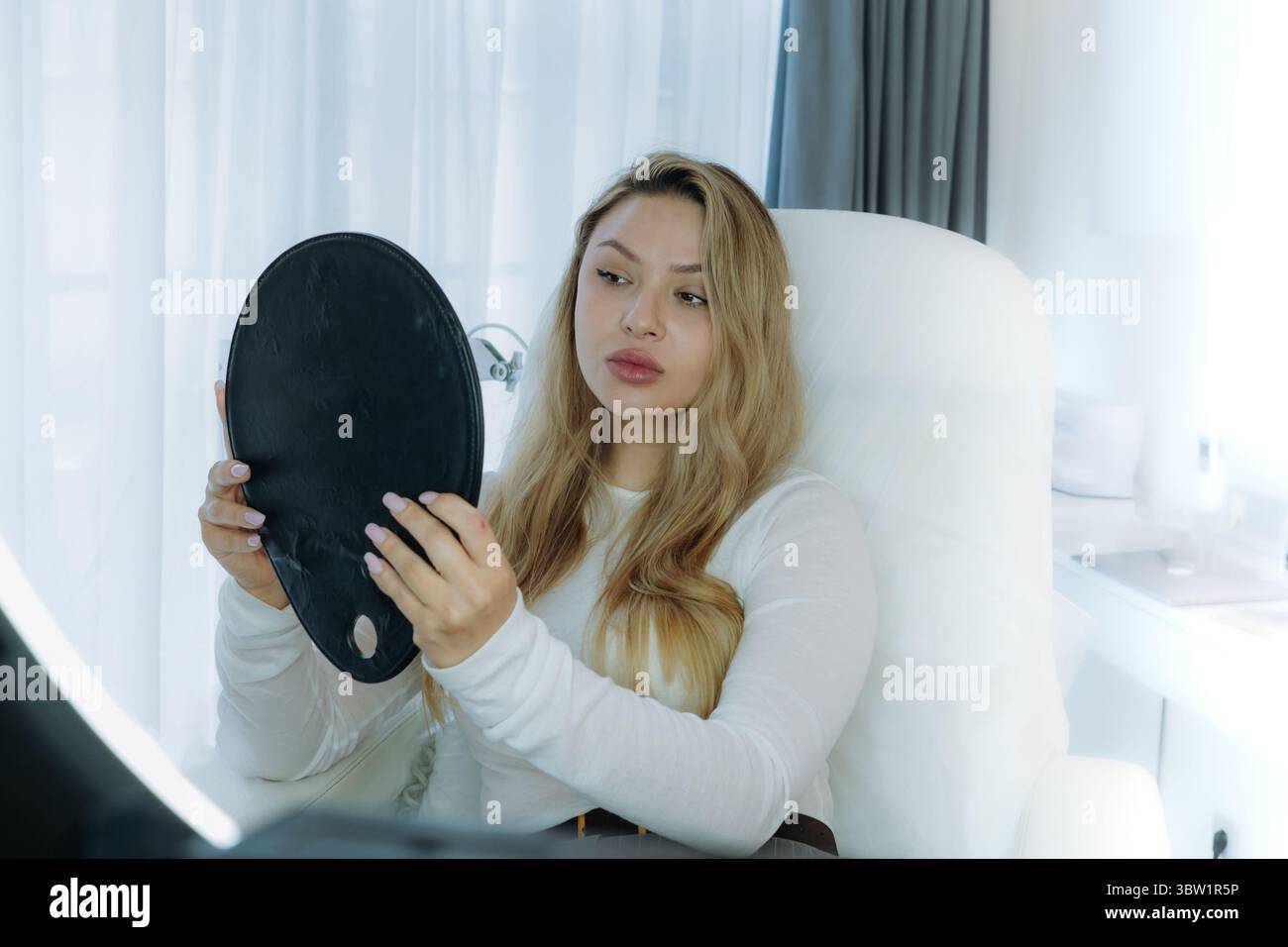 femme regardant dans un miroir après une procédure de rajeunissement facial à la clinique esthétique Banque D'Images