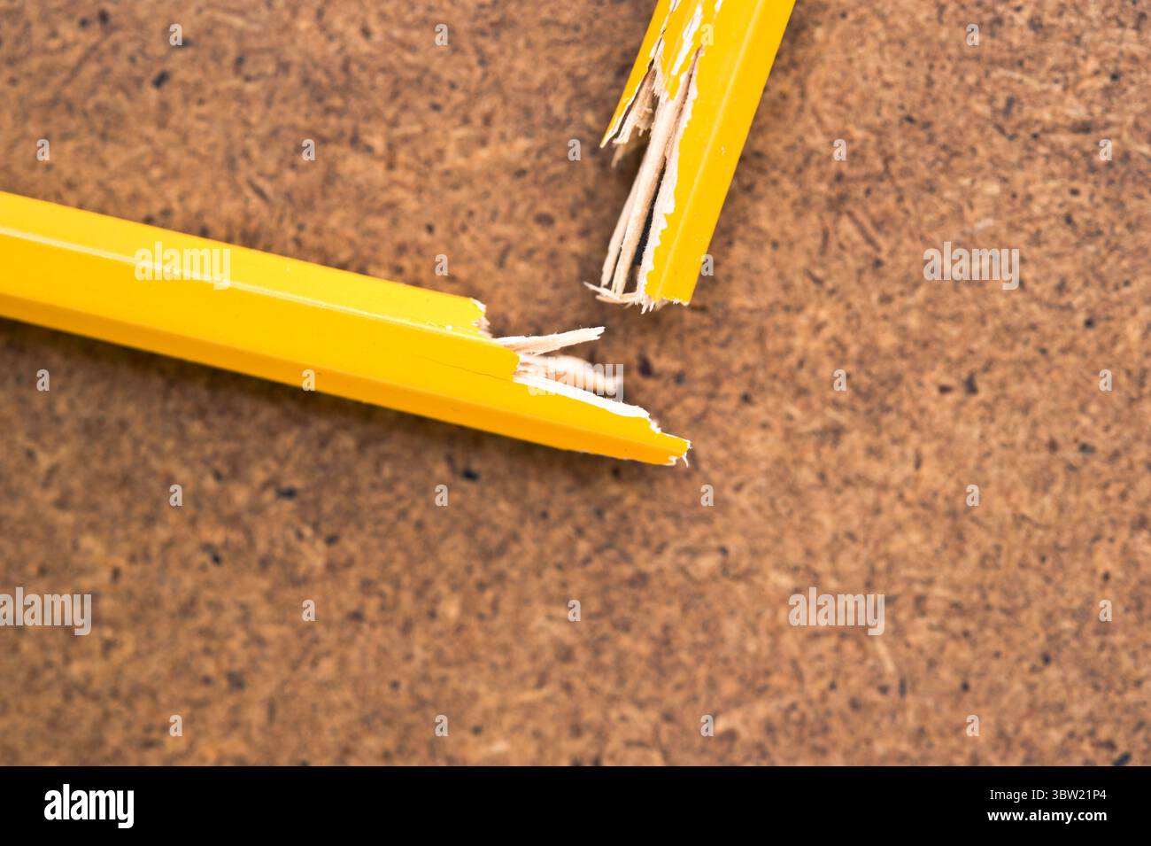 Gros plan d'un crayon jaune cassé sur un panneau de liège, symbolisant la frustration et le stress Banque D'Images