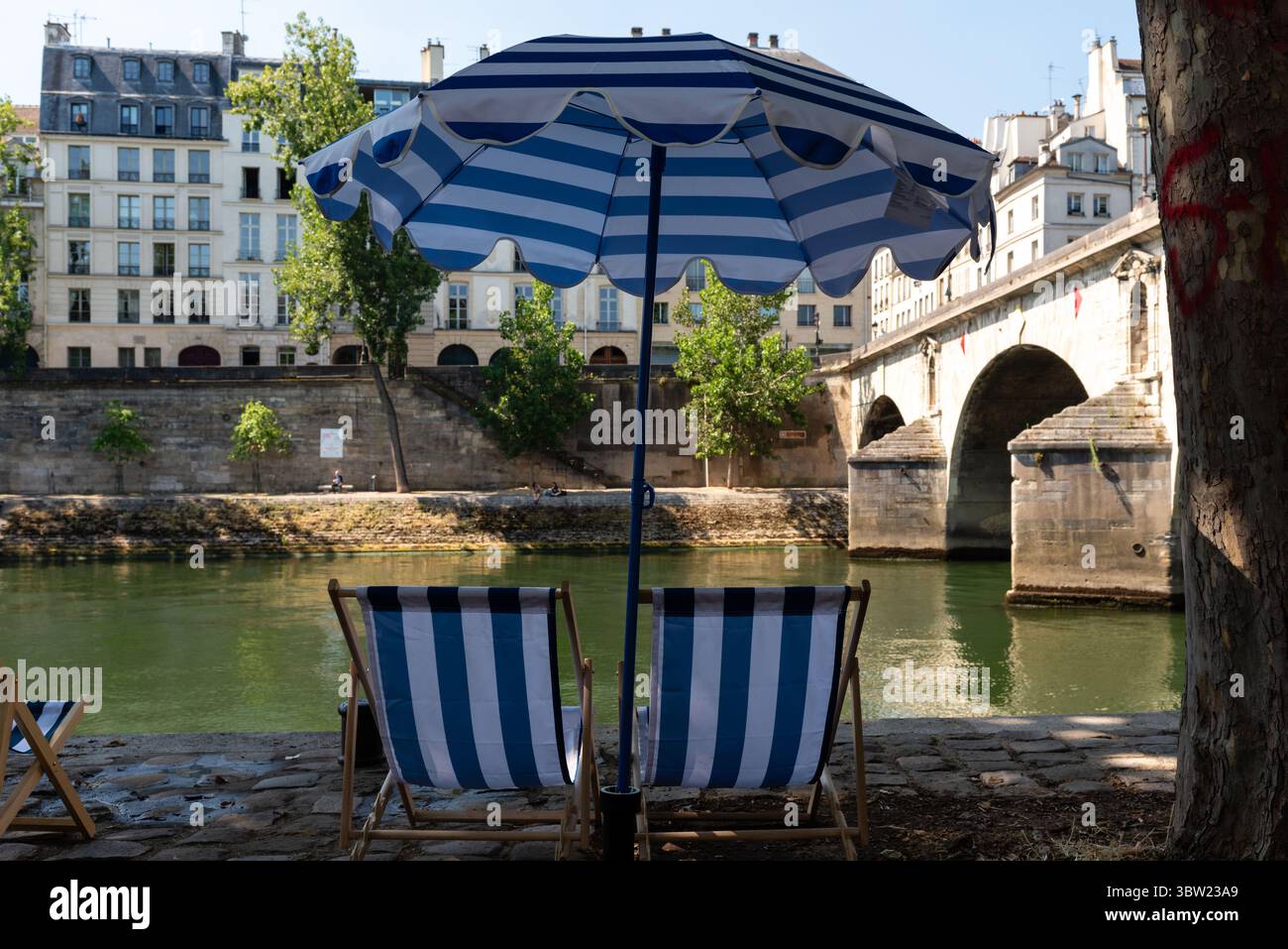 Chaises de plage rayées bleues et blanches et parasol sur la rive de la Seine pour Paris plage, une plage artificielle le long de la Seine Banque D'Images