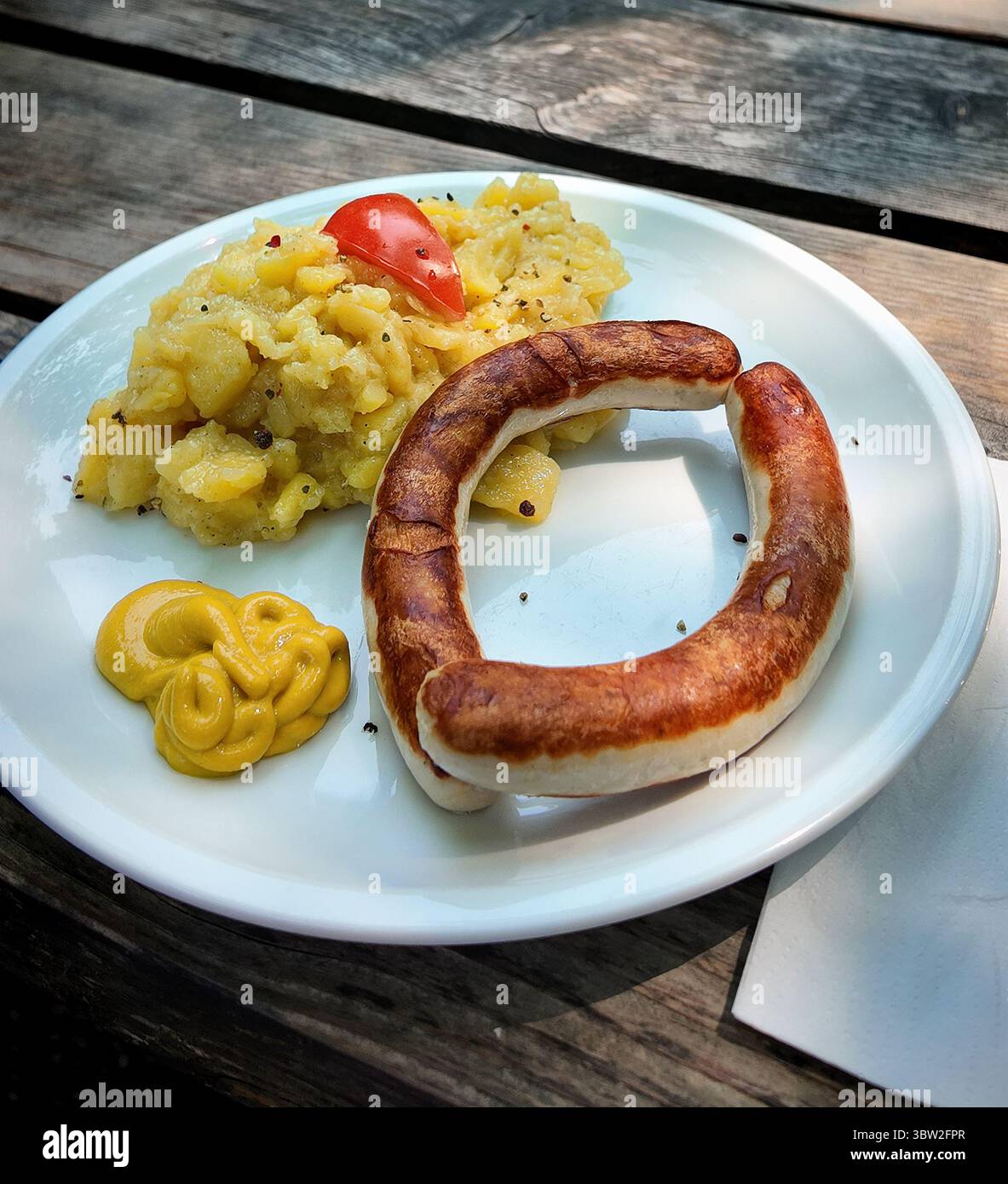 Cuisine bavaroise typique dans le café en plein air : saucisse grillée de porc ( Bratwurst) avec salade de pommes de terre et moutarde servie sur une table rustique en bois à l'extérieur Banque D'Images