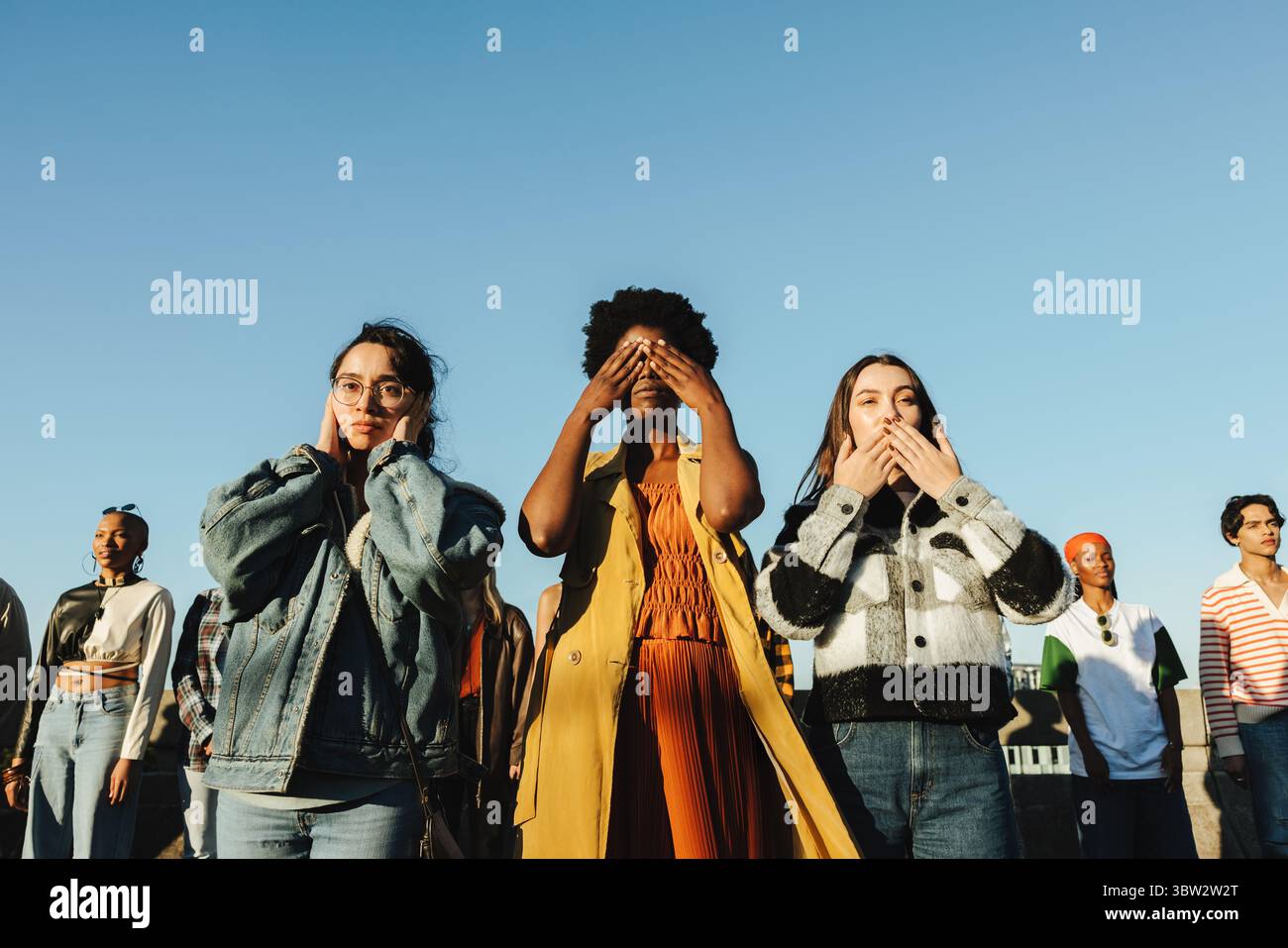 Des jeunes exprimant le concept des trois singes sages lors d'une manifestation en plein air. Ils symbolisent entendre, voir et parler positivement, en promouvant U. Banque D'Images