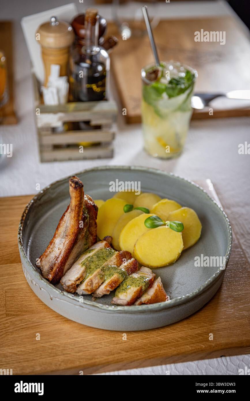 Côtelette de porc grillée tranchée avec pommes de terre et sauce pesto sur la table du restaurant Banque D'Images