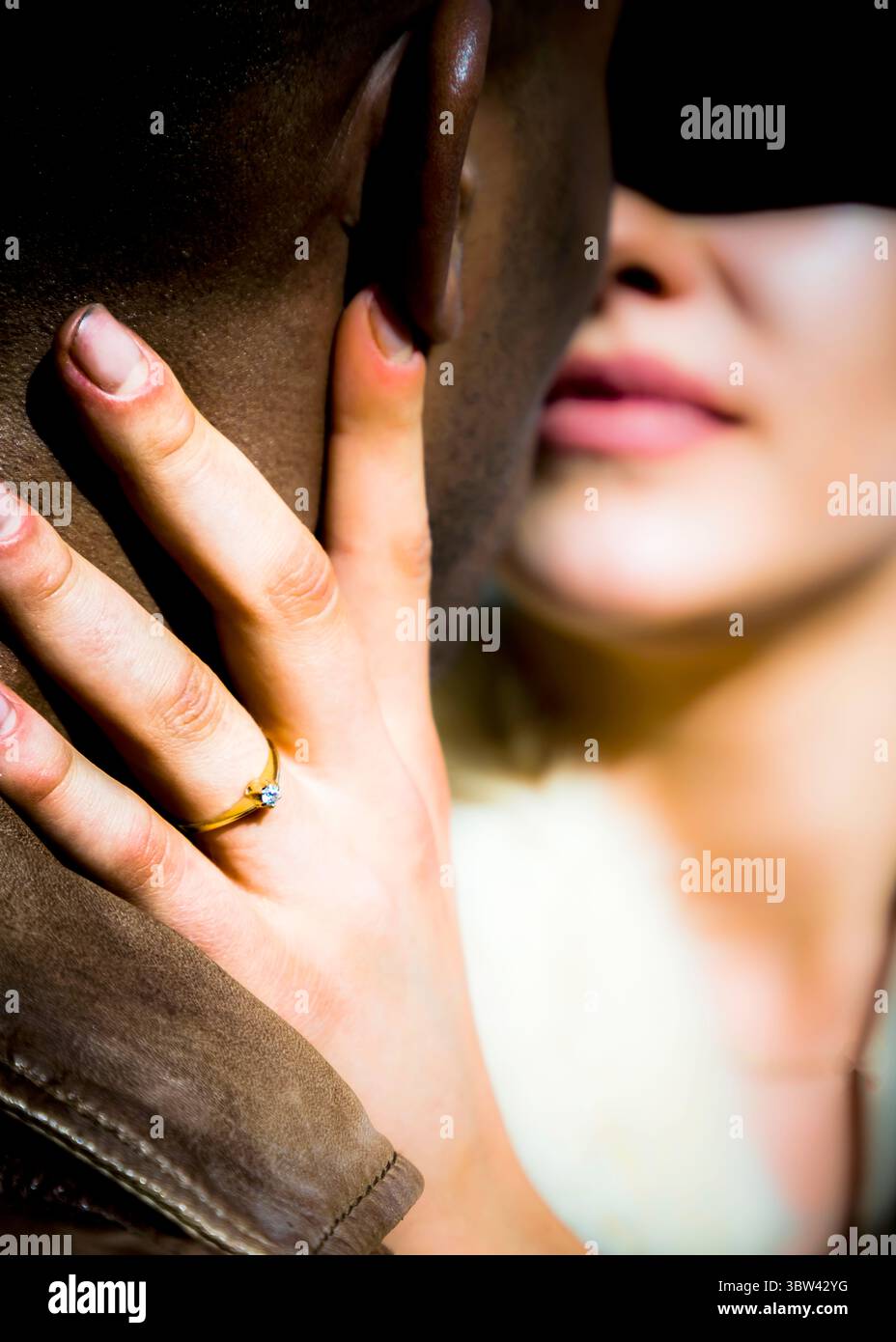 La main d'une femme, ornée d'un anneau, touche doucement le cou d'un homme. L'accent est mis sur la main et l'anneau, avec la peau de l'homme et le visage de la femme flous Banque D'Images