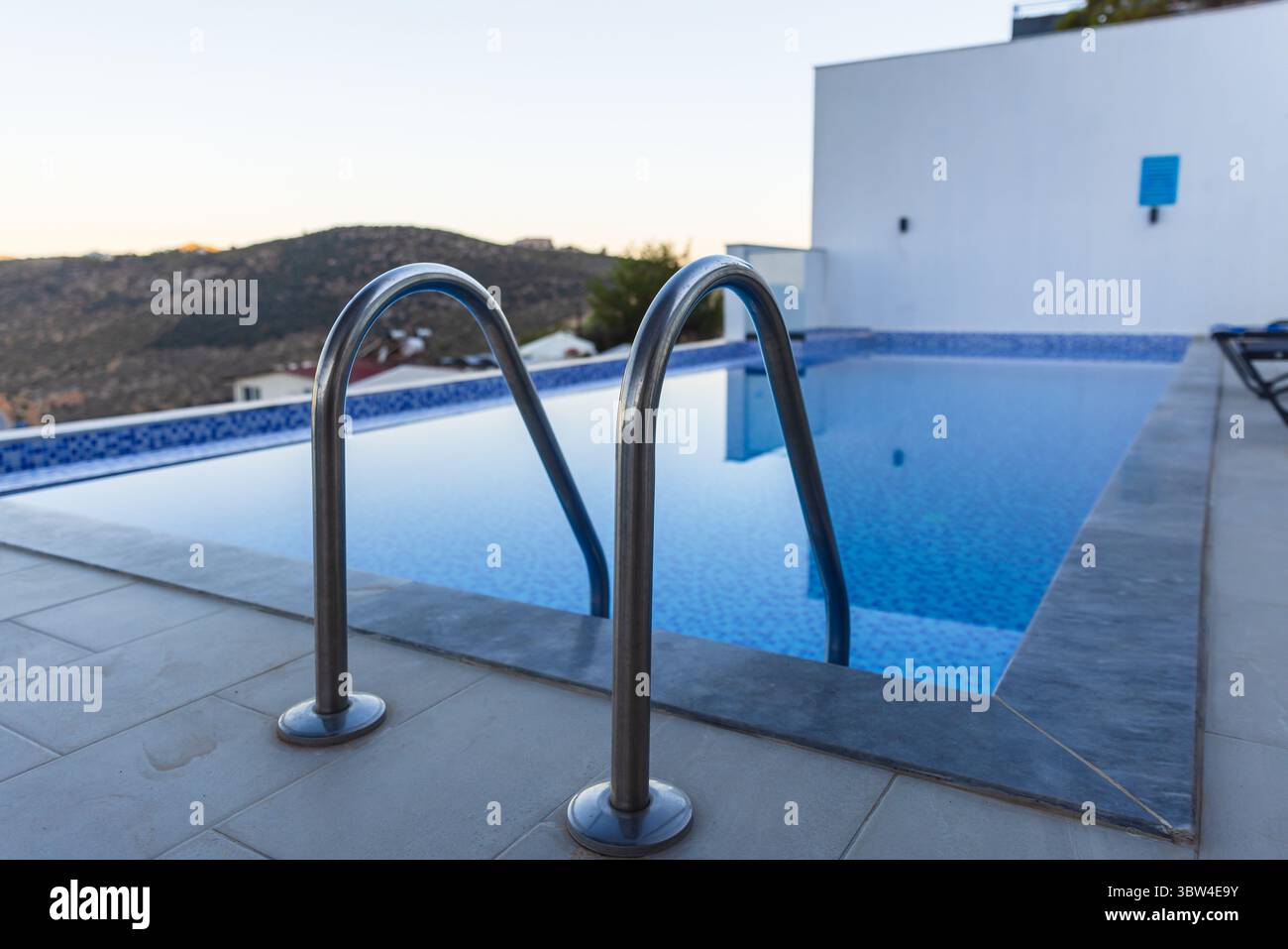 Une piscine extérieure luxueuse avec des mains courantes en acier inoxydable surplombant un paysage montagneux pittoresque Banque D'Images
