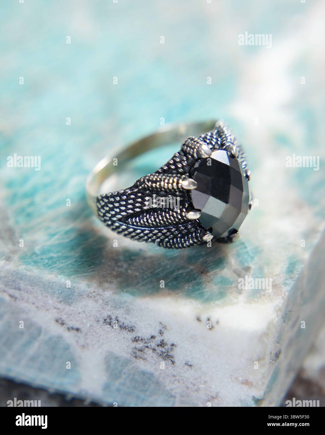 Bague en argent avec pierre précieuse noire et conception de griffe reposant sur la pierre amazonite Banque D'Images