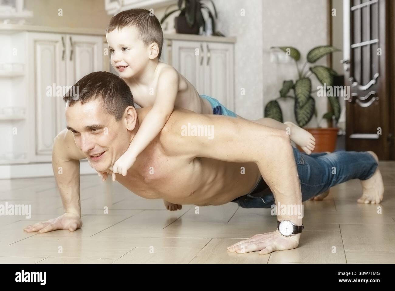 Papa et son fils font des push-up depuis le sol dans la chambre de la maison. L'enfant repose sur le dos de son père. Activité physique à la maison. Un bon modèle. A Banque D'Images