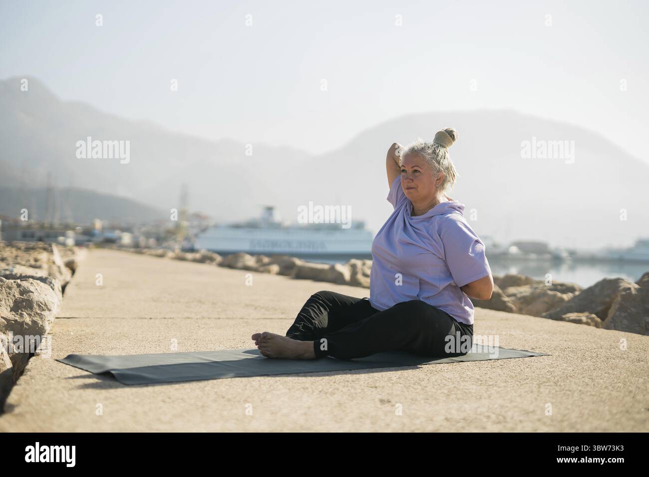 Femme mûre avec des dreadlocks s'entraîner à faire des exercices de yoga sur la plage de mer Copy espace - bien-être bien-être et âge actif de personnes âgées concept Banque D'Images