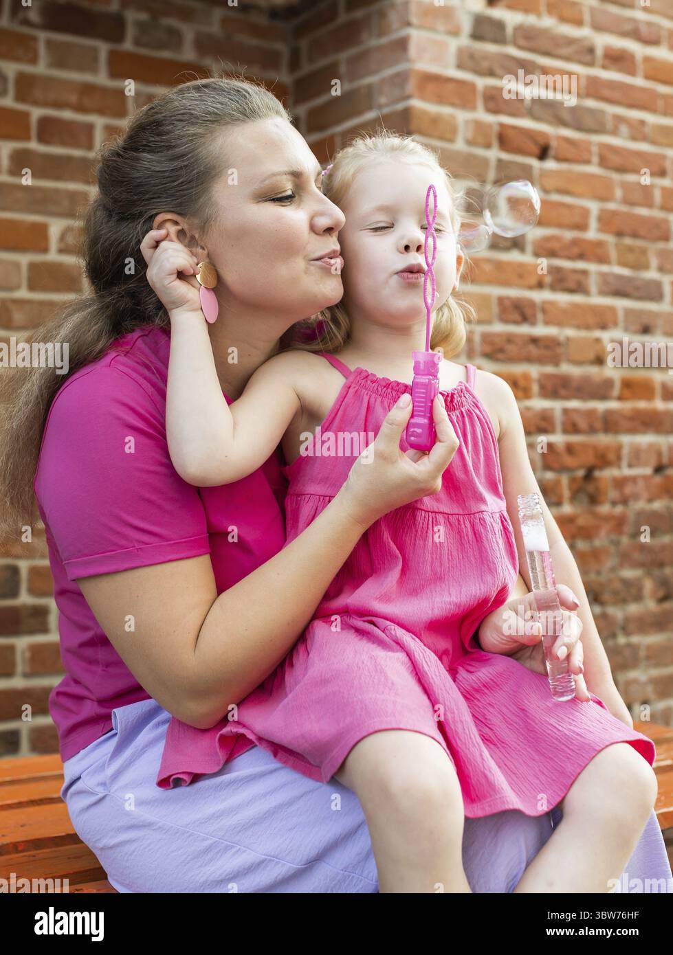 Blondes kleines Maedchen mit cochlea Implantat spielen mit ihrer Mutter im Freien. Hoeren Beeintraechtigung taub und Gesundheit Konzept. Vielfalt und Banque D'Images