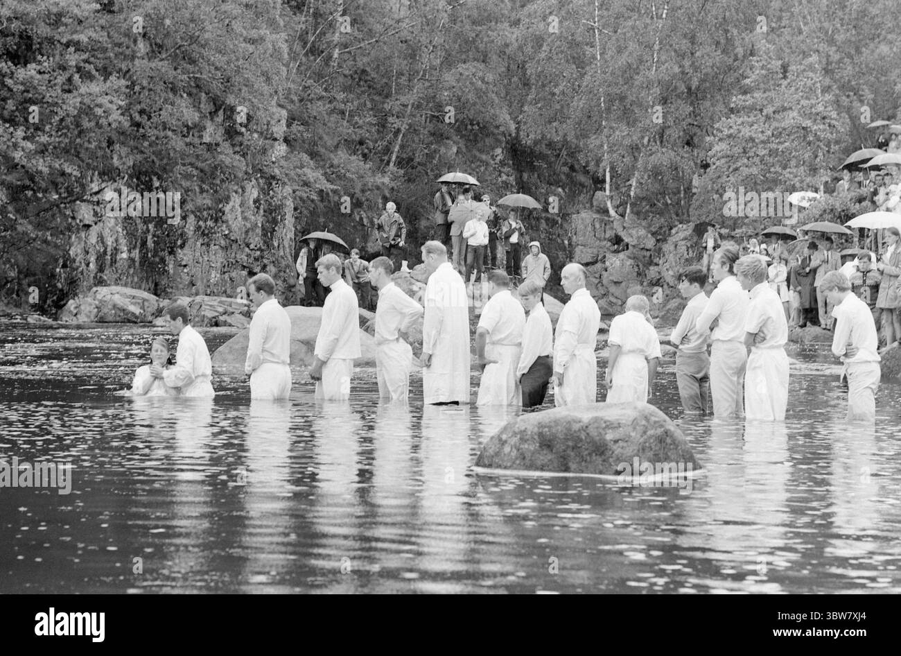 Current 31-1-1970 : Hallelujah pour des millions. Dans la vallée de Sharon il y a une activité animée toute l'année. Les pentecôtistes ont leur propre imprimerie, école biblique et immeuble de bureaux. Ils aident la mission dans 70 pays et disposent d'un budget annuel de 2,5 millions d'euros. Les pentecôtistes baptisent seulement les croyants, c’est-à-dire les gens qui croient qu’ils sont sauvés. Le baptême est donc un grand jour dans la vie des pentecôtistes. Le baptême dans la vallée de Sharon a eu lieu un dimanche pluvieux dans la rivière qui traverse la vallée. Il y avait 26 personnes qui se sont présentées dans leurs robes blanches. Ils ont été baptisés Banque D'Images
