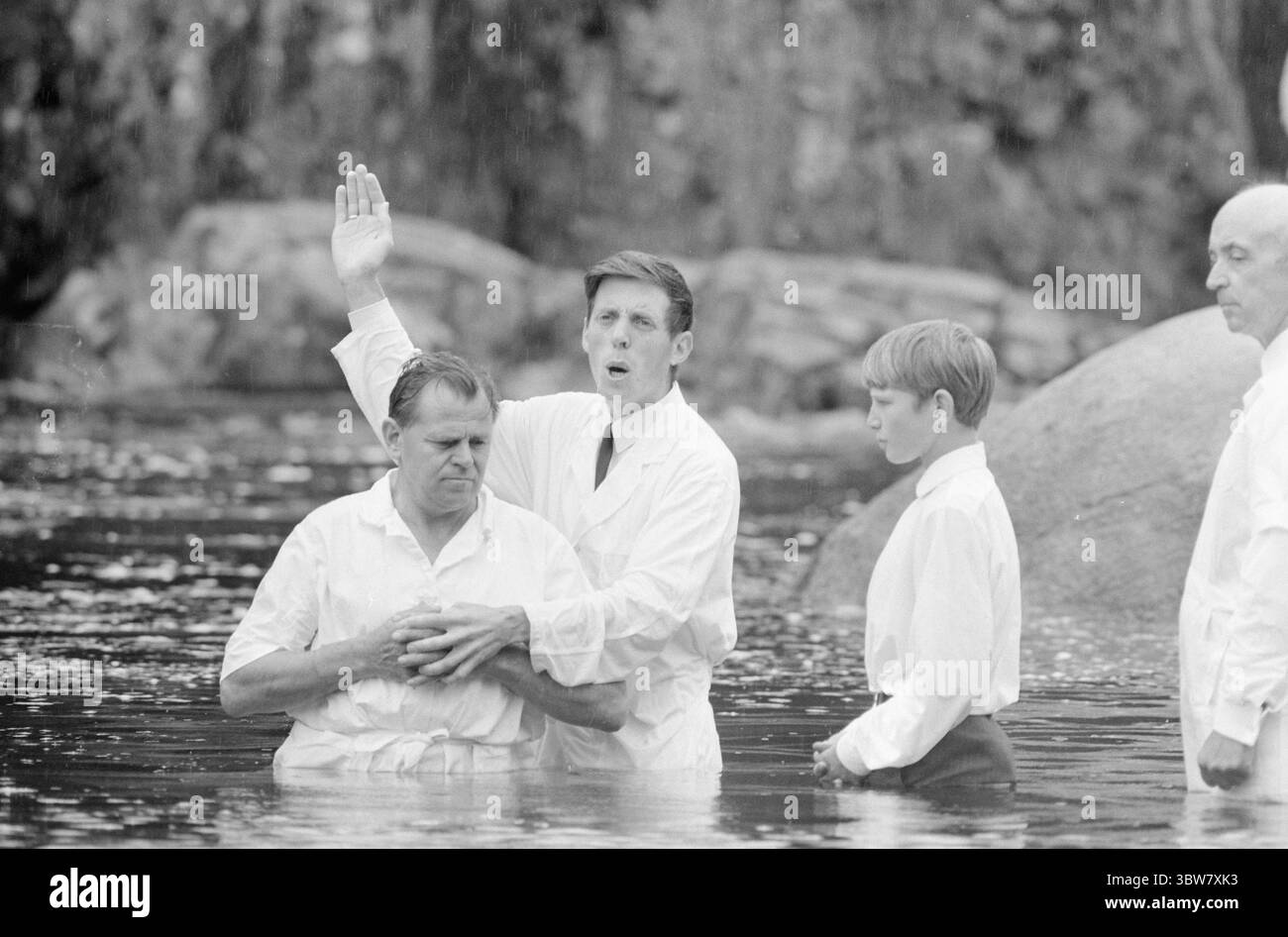 Current 31-1-1970 : Hallelujah pour des millions. Dans la vallée de Sharon il y a une activité animée toute l'année. Les pentecôtistes ont leur propre imprimerie, école biblique et immeuble de bureaux. Ils aident la mission dans 70 pays et disposent d'un budget annuel de 2,5 millions d'euros. Les pentecôtistes baptisent seulement les croyants, c’est-à-dire les gens qui croient qu’ils sont sauvés. Le baptême est donc un grand jour dans la vie des pentecôtistes. Le baptême dans la vallée de Sharon a eu lieu un dimanche pluvieux dans la rivière qui traverse la vallée. Il y avait 26 personnes qui se sont présentées dans leurs robes blanches. Ils ont été baptisés Banque D'Images