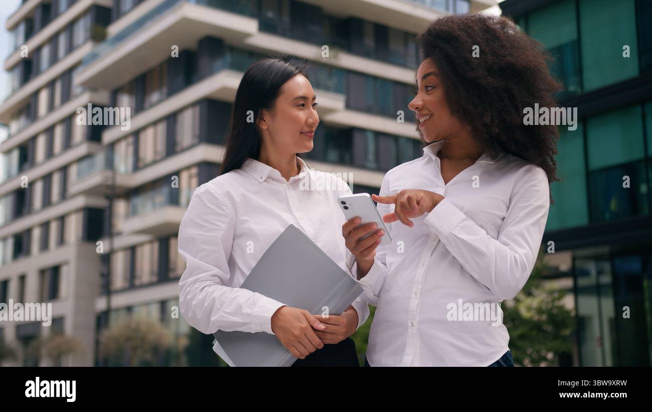 Afro-américaine asiatique coréenne femmes collègues femmes d'affaires entreprises utilisant le téléphone mobile smartphone en ligne discuter parler des médias sociaux Banque D'Images