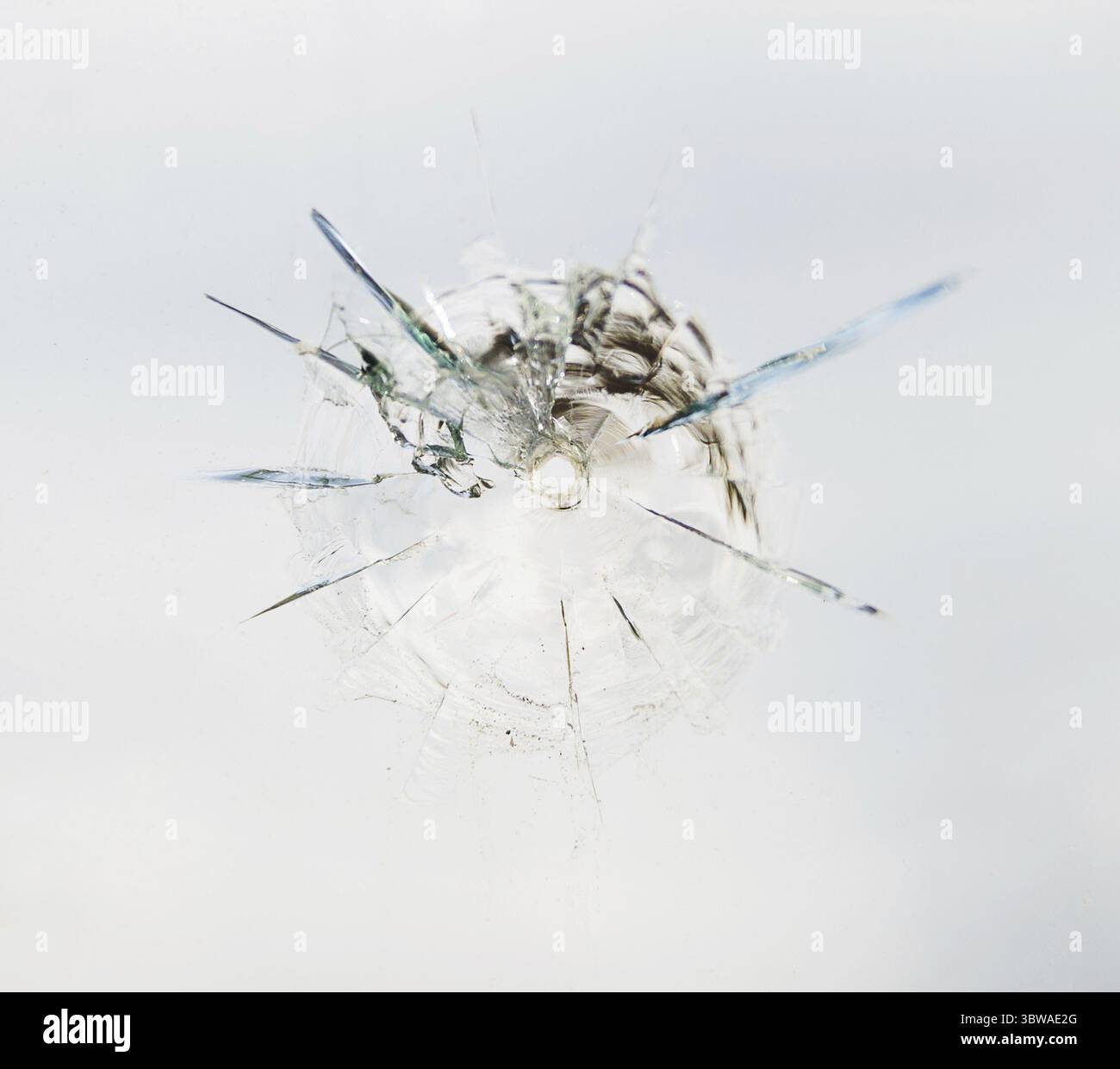 Trou de balle rond dans le verre avec des fissures radiales Banque D'Images