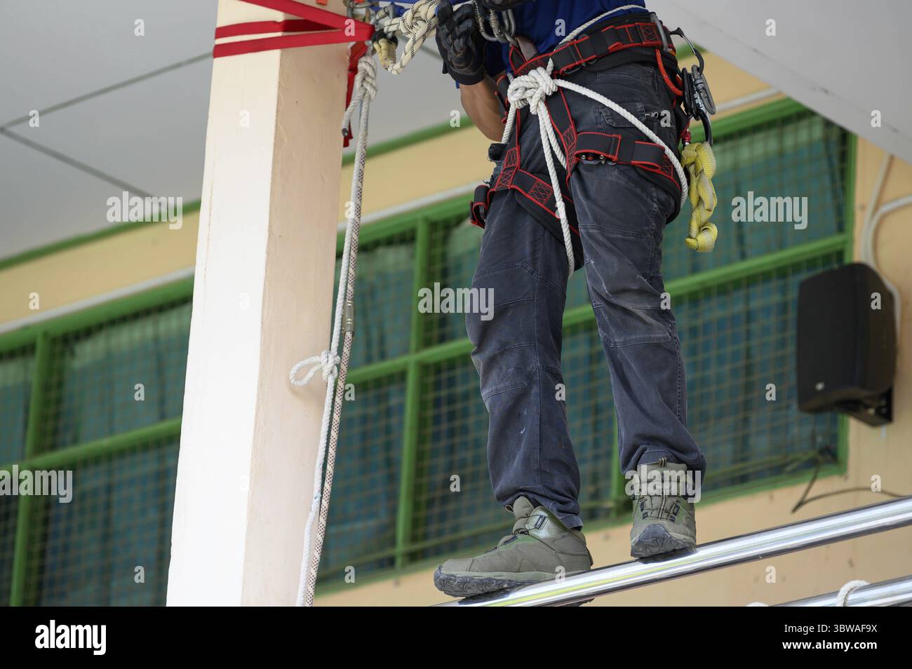 Gros plan de la formation du bas du corps des pompiers pour l'exercice d'incendie en montrant comment échapper au bâtiment en feu avec une corde de sécurité correctement. Sécurité INS Banque D'Images