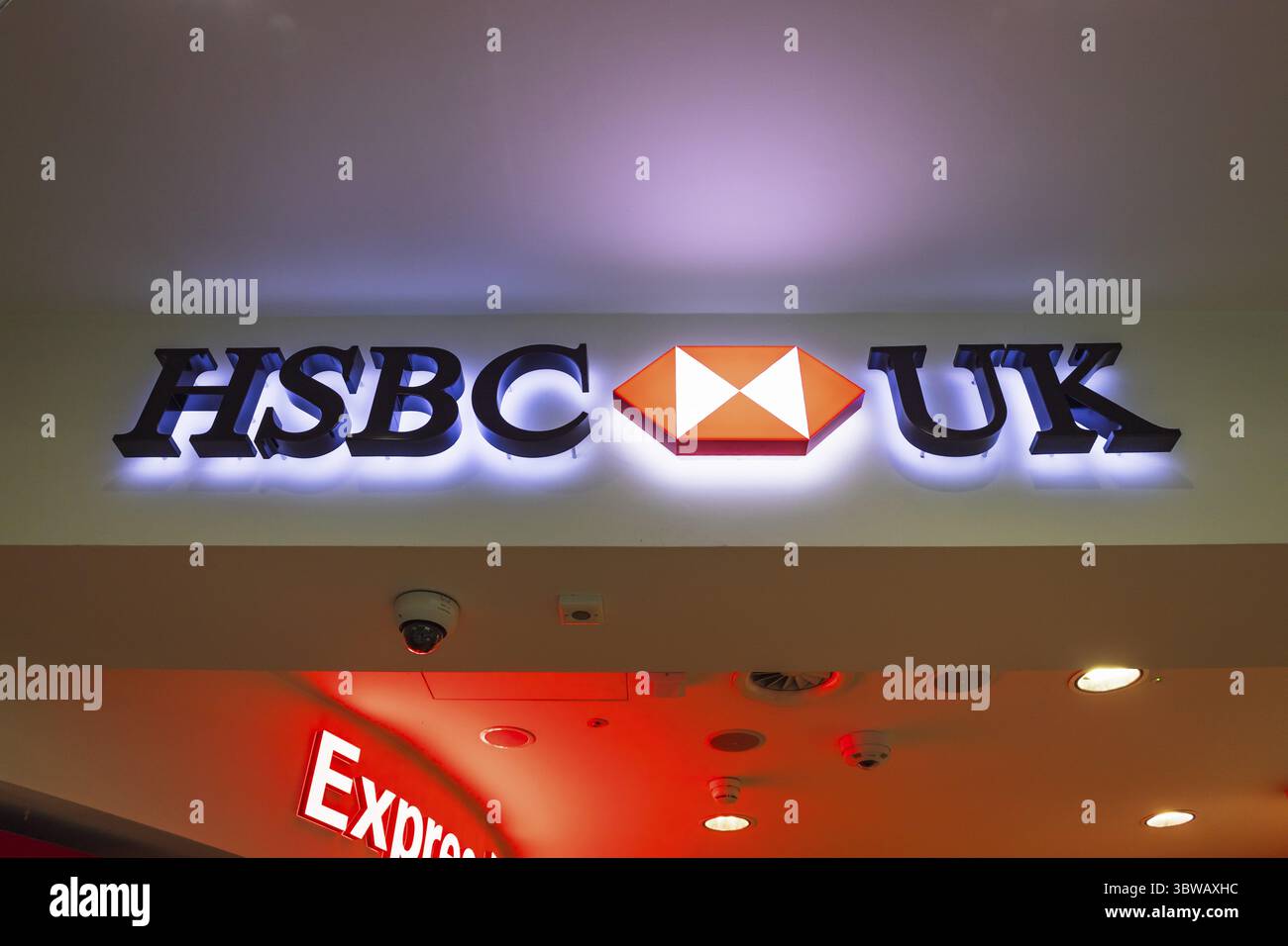 Logo de banque HSBC Royaume-Uni allumé au-dessus d'une succursale bancaire à l'intérieur d'un espace commercial ou de vente au détail. Londres, Royaume-Uni, 24 décembre 2023 Banque D'Images