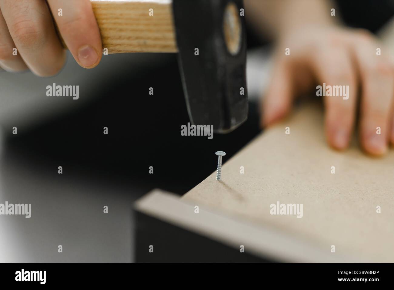 Gros plan de martelage d'un clou dans une planche de bois Banque D'Images