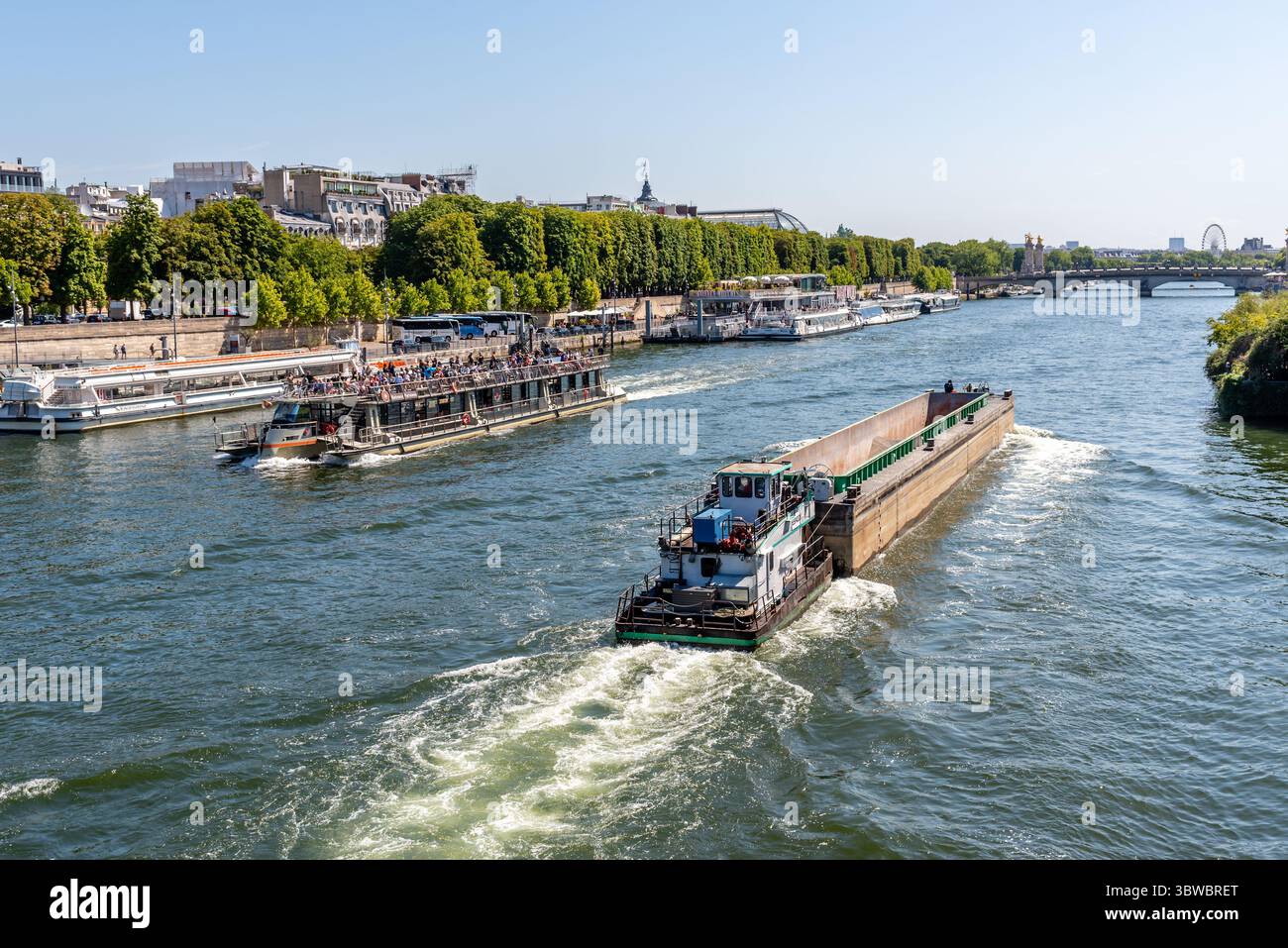 Paris, France, 07.09.2025. Une barge de fret et un bateau de plaisance sur la Seine par une journée ensoleillée d'été Banque D'Images