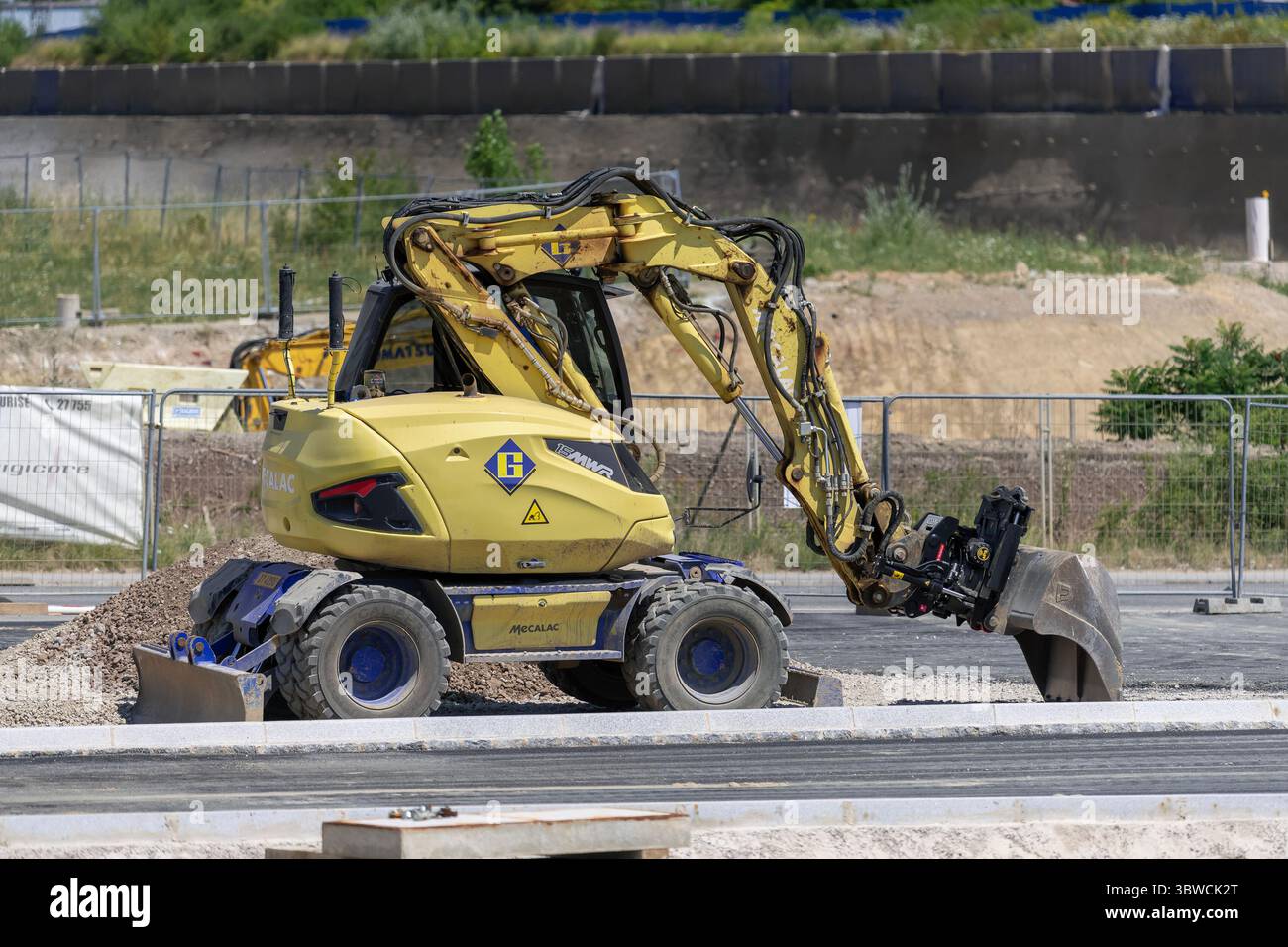 Wickrange, Luxembourg - vue sur une pelle sur roues jaune Mecalac 15MWR pour travaux de terrassement sur un chantier. Banque D'Images
